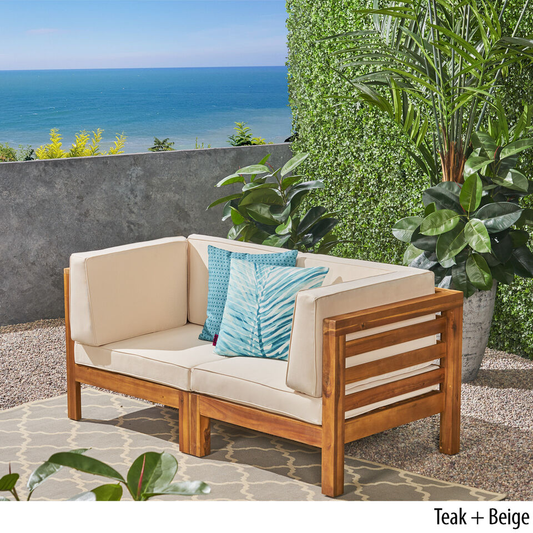Modern teak patio loveseat with cream cushions and decorative blue pillows