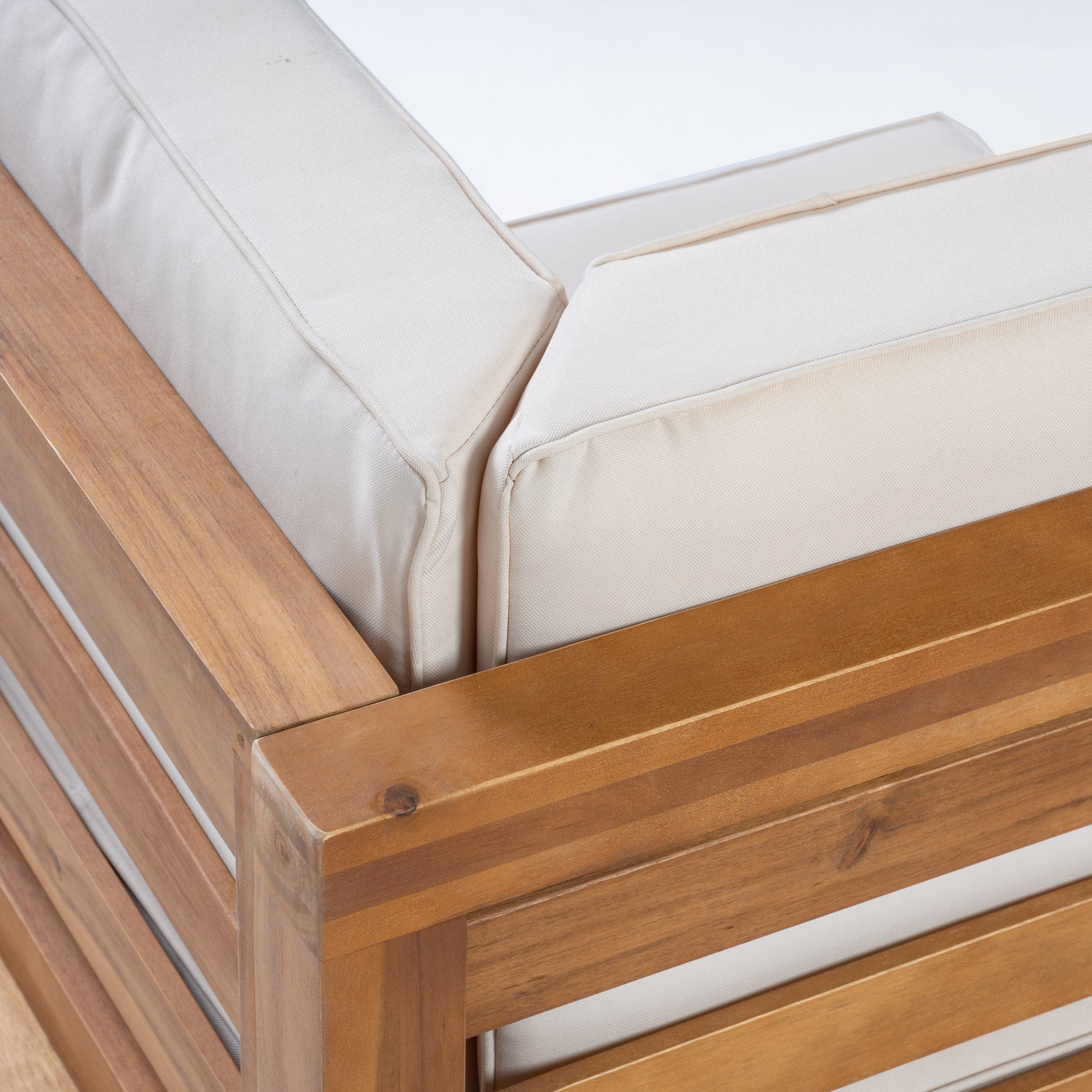 Closeup of a natural wood patio chair frame with thick creamcolored cushions