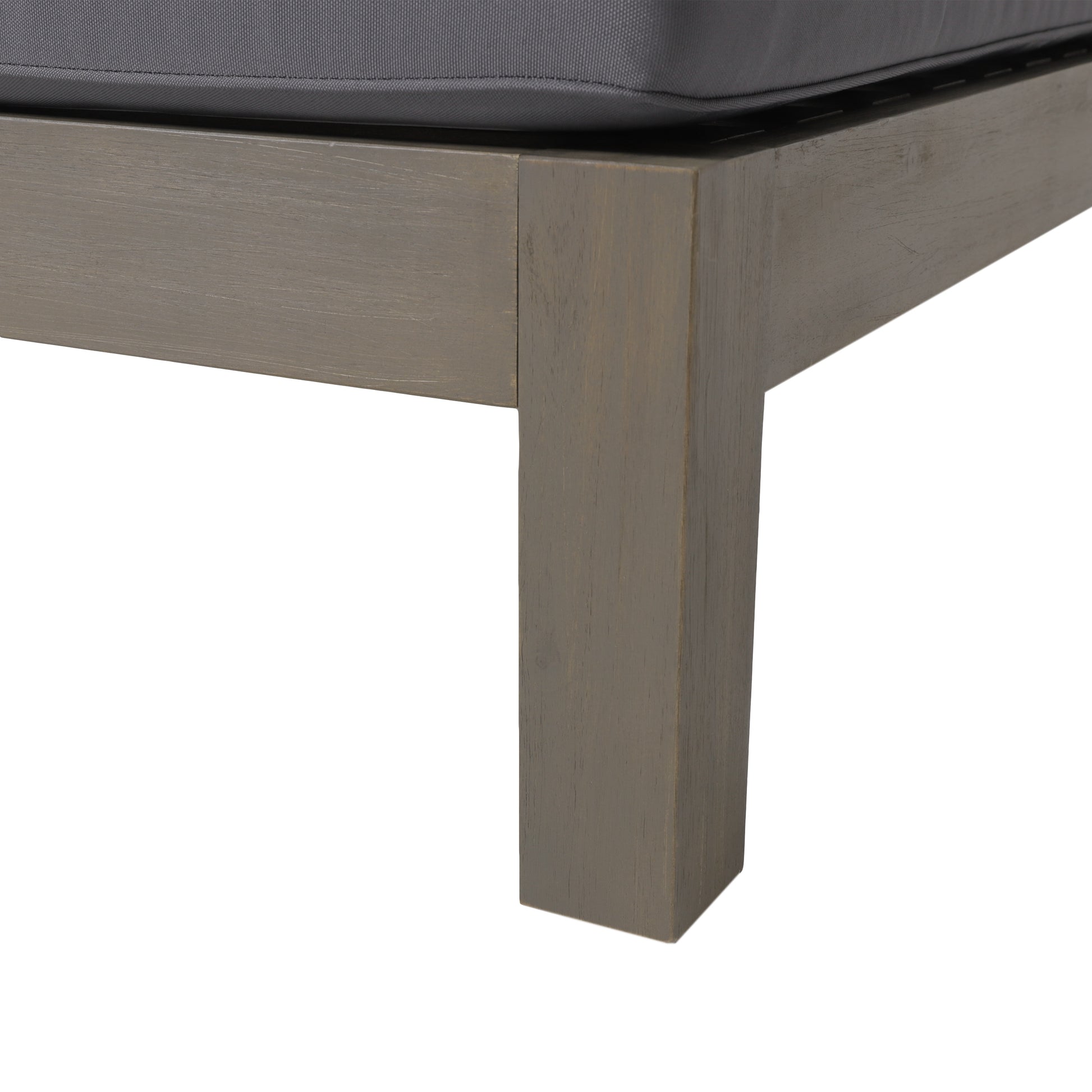 Closeup of grey wooden frame corner with dark grey cushion of an outdoor chaise lounge