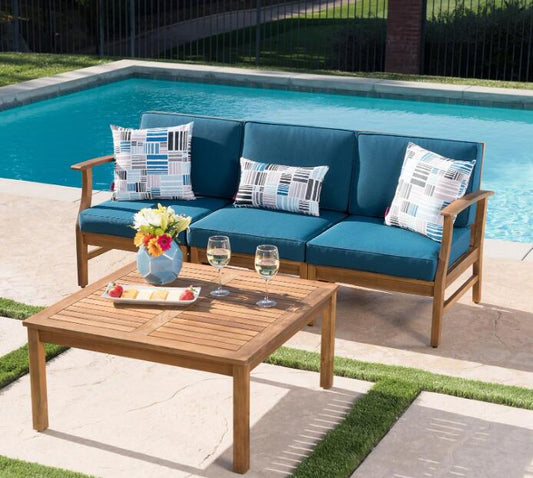 Teal outdoor sofa with geometric print cushions and wooden frame by pool