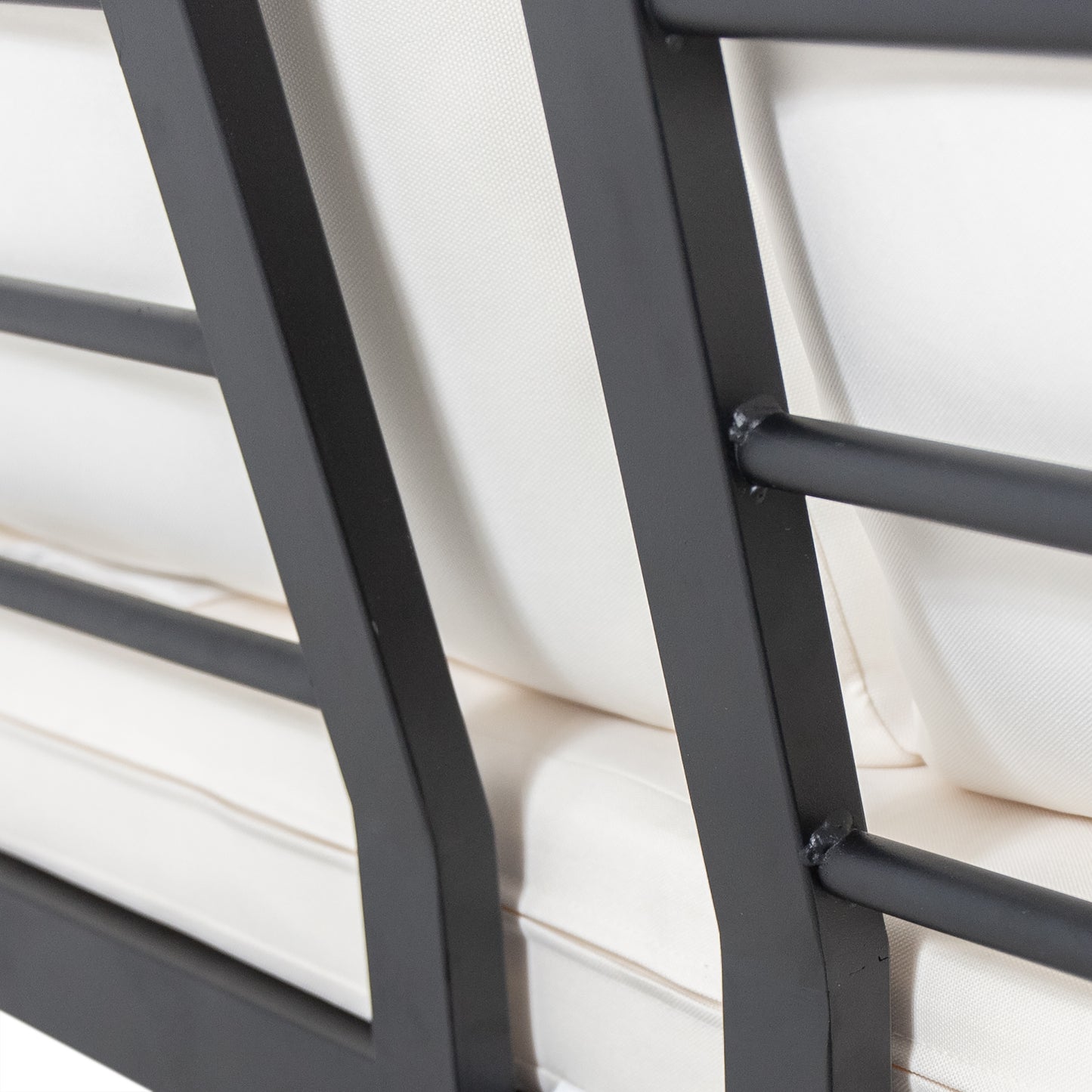 Closeup of a black metal frame patio sofa with cream cushions