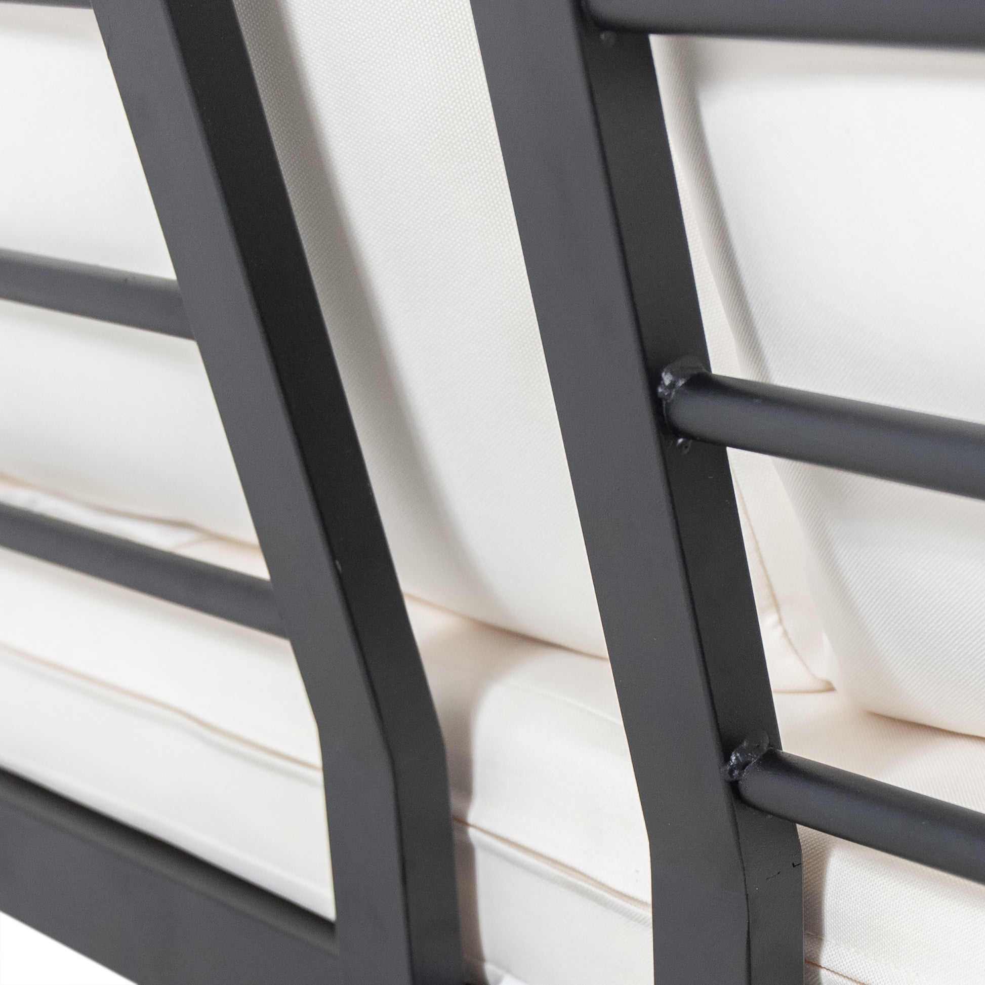 Closeup of a black metal frame patio sofa with cream cushions