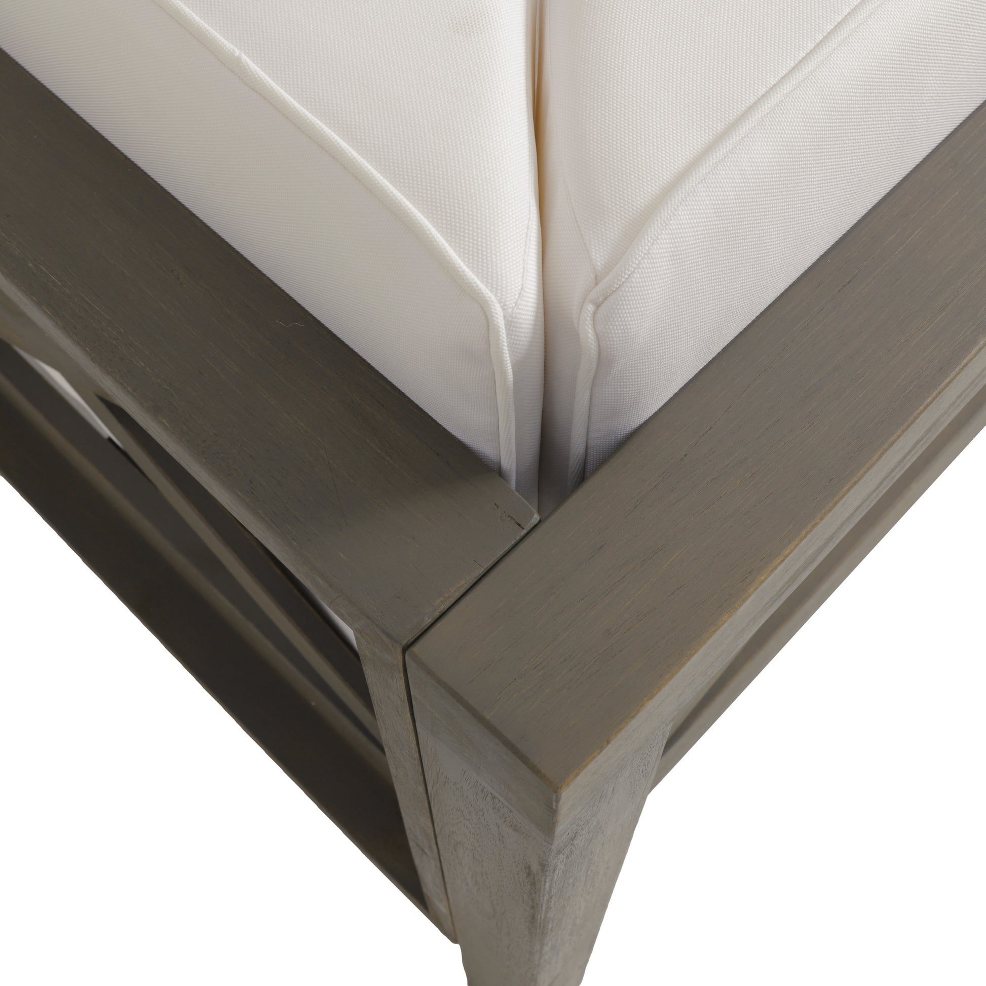 Closeup of a wooden sectional sofa frame with plush white cushions showing detailed joinery