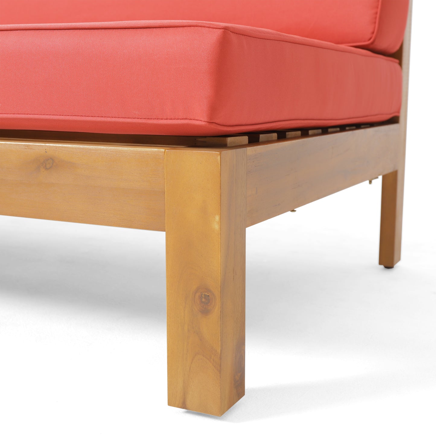 Corner detail of a teak wood patio lounge chair with coral red cushions