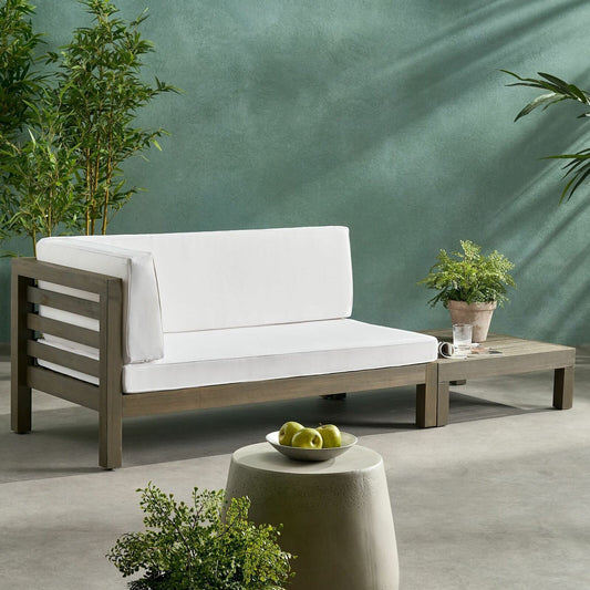 Grey wood outdoor sectional sofa with plush white cushions on a patio setting