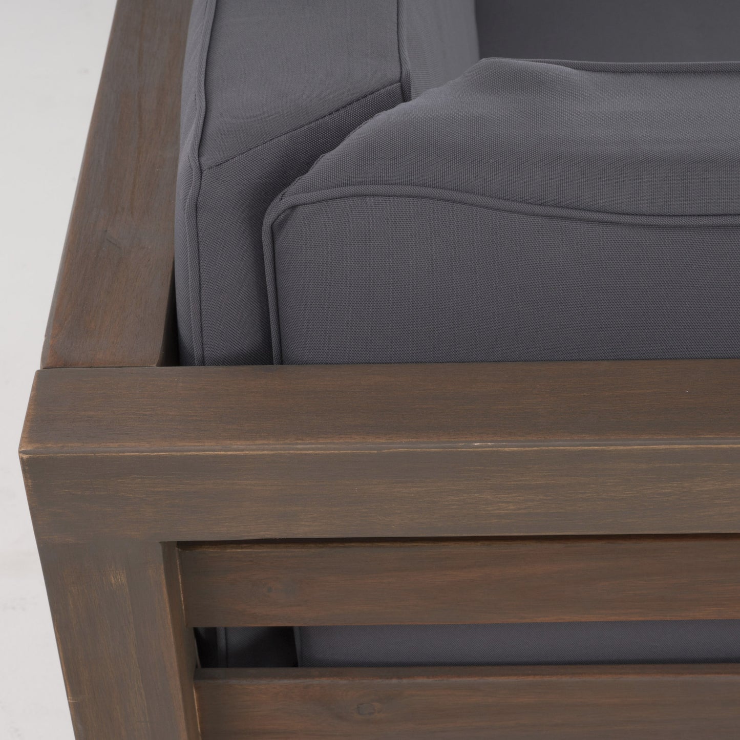 Closeup of charcoal gray outdoor sofa cushions with a dark wood frame detail