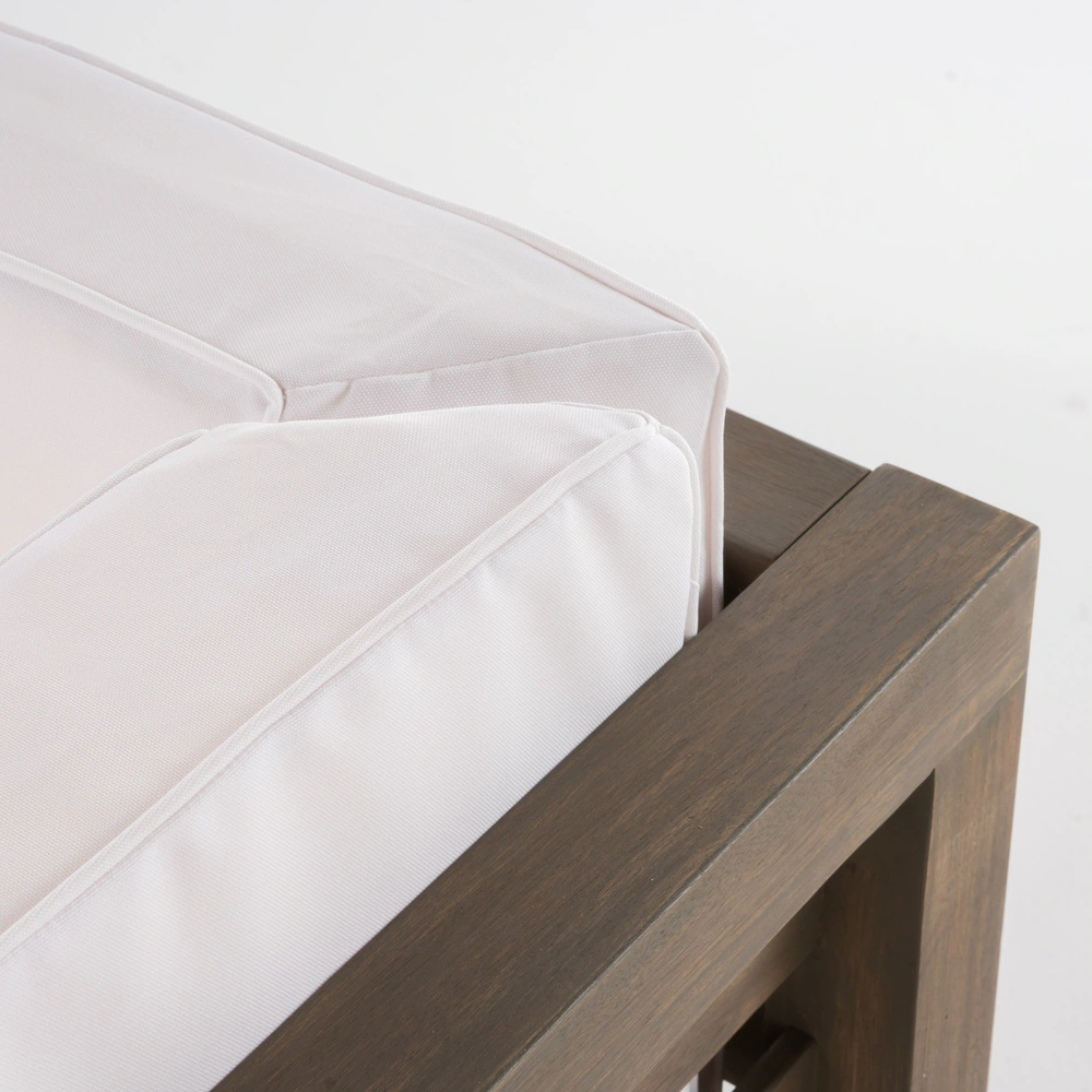 Closeup of plush white outdoor sofa cushions with piped edges on a dark wood frame
