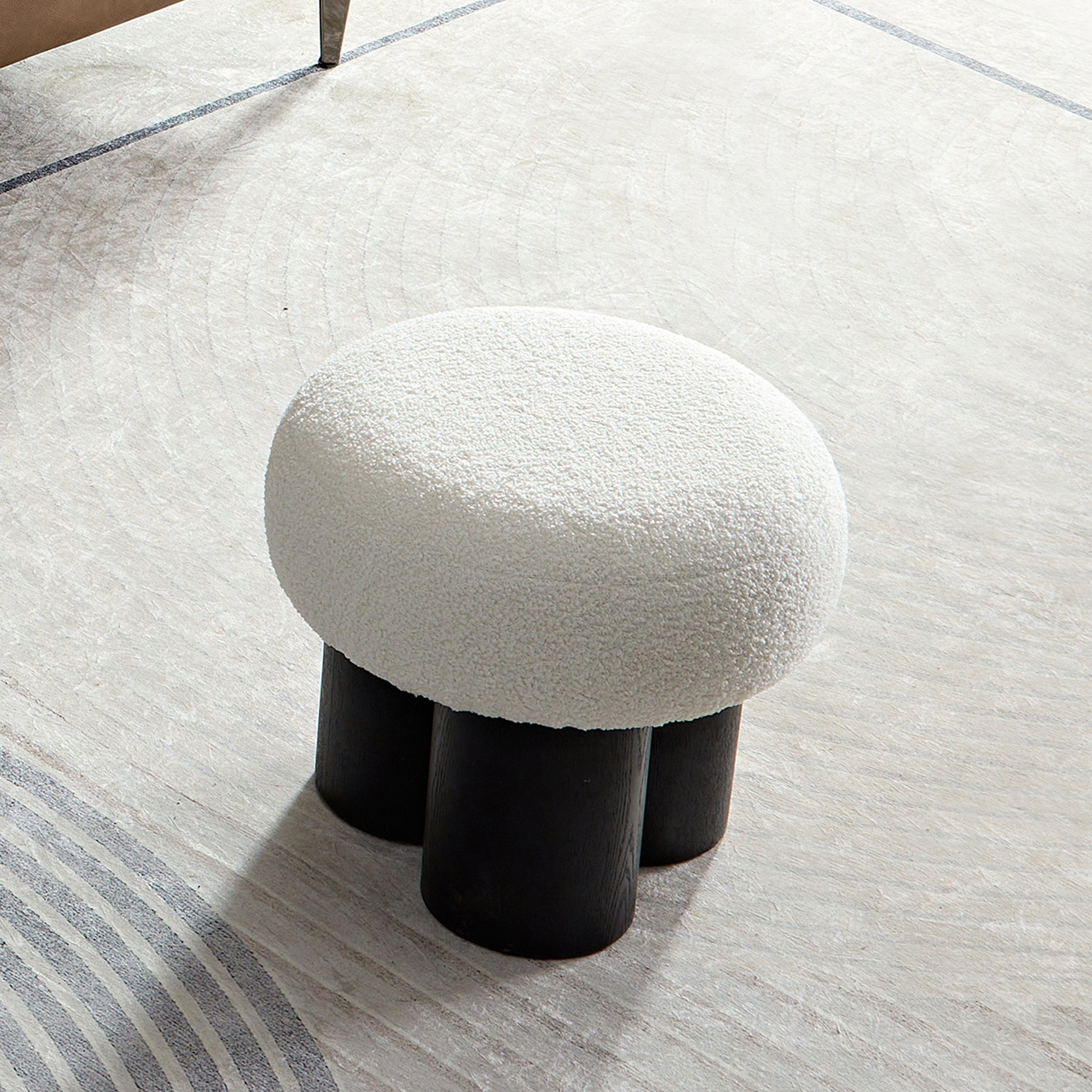 White boucle ottoman with three black wooden legs a contemporary accent stool