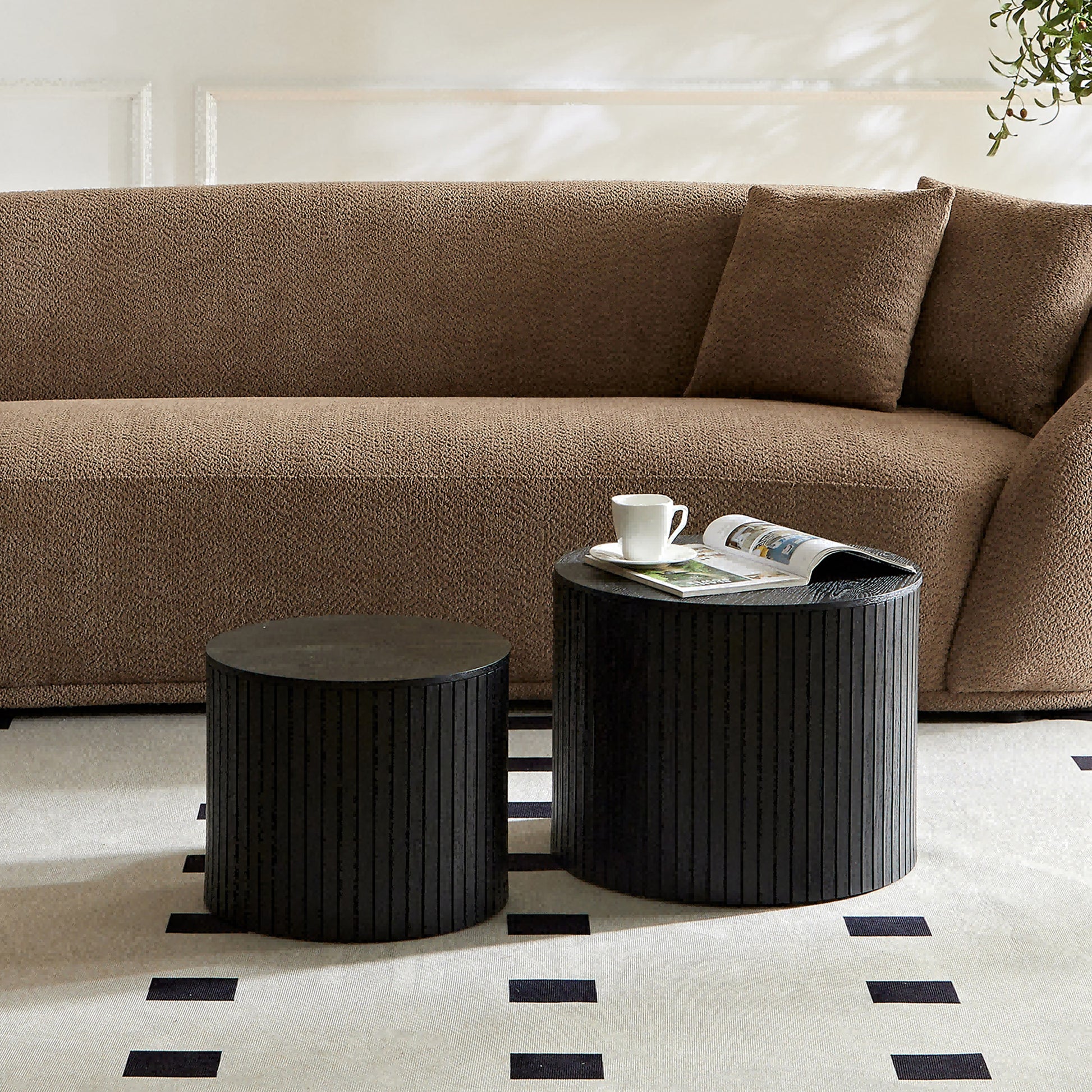 Black ribbed cylindrical side table with a magazine and cup
