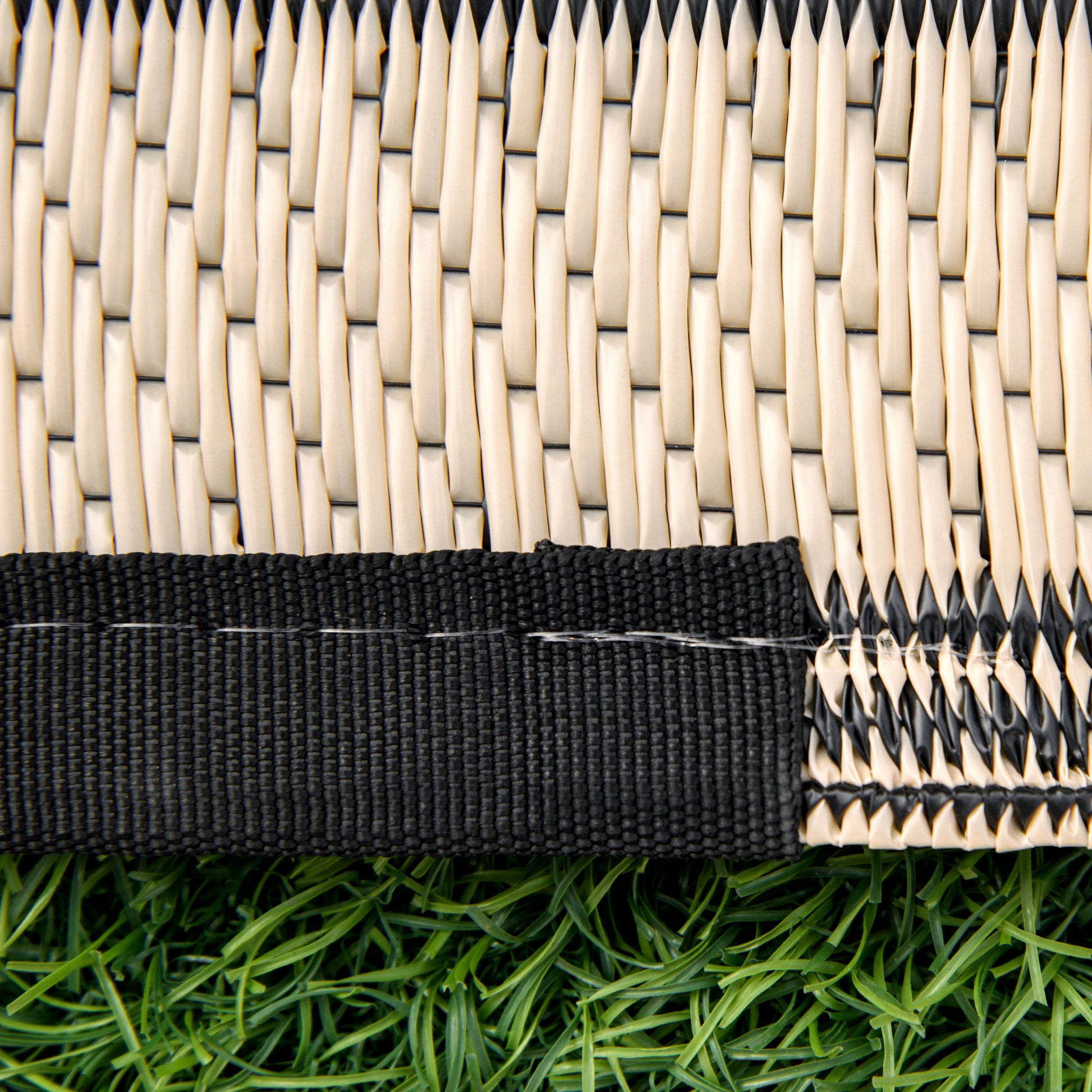 Closeup of woven strawlike texture with black trim on artificial grass mat