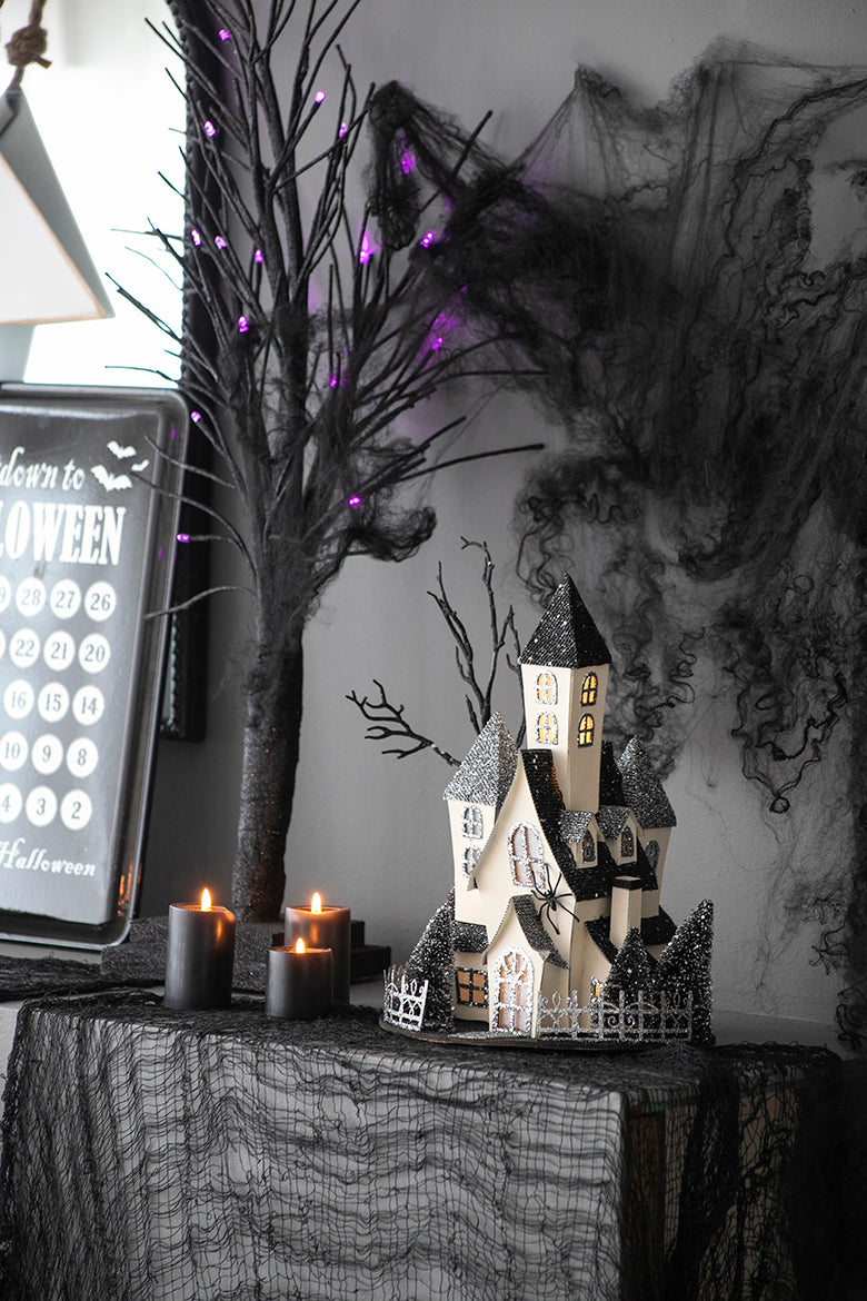 Illuminated spooky haunted house centerpiece with black glitter accents and small trees