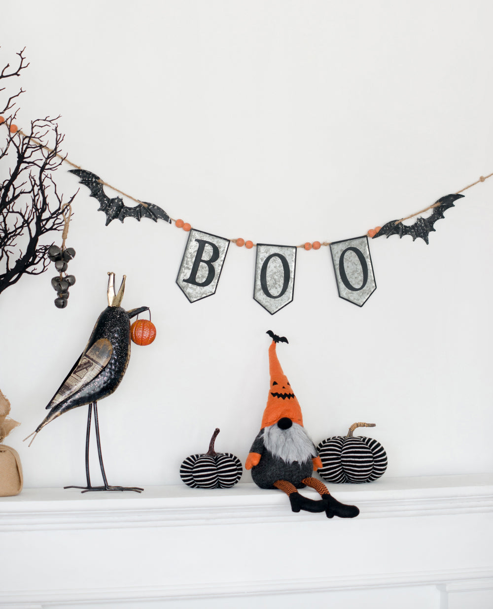 Black metal raven holding orange pumpkin for Halloween decor