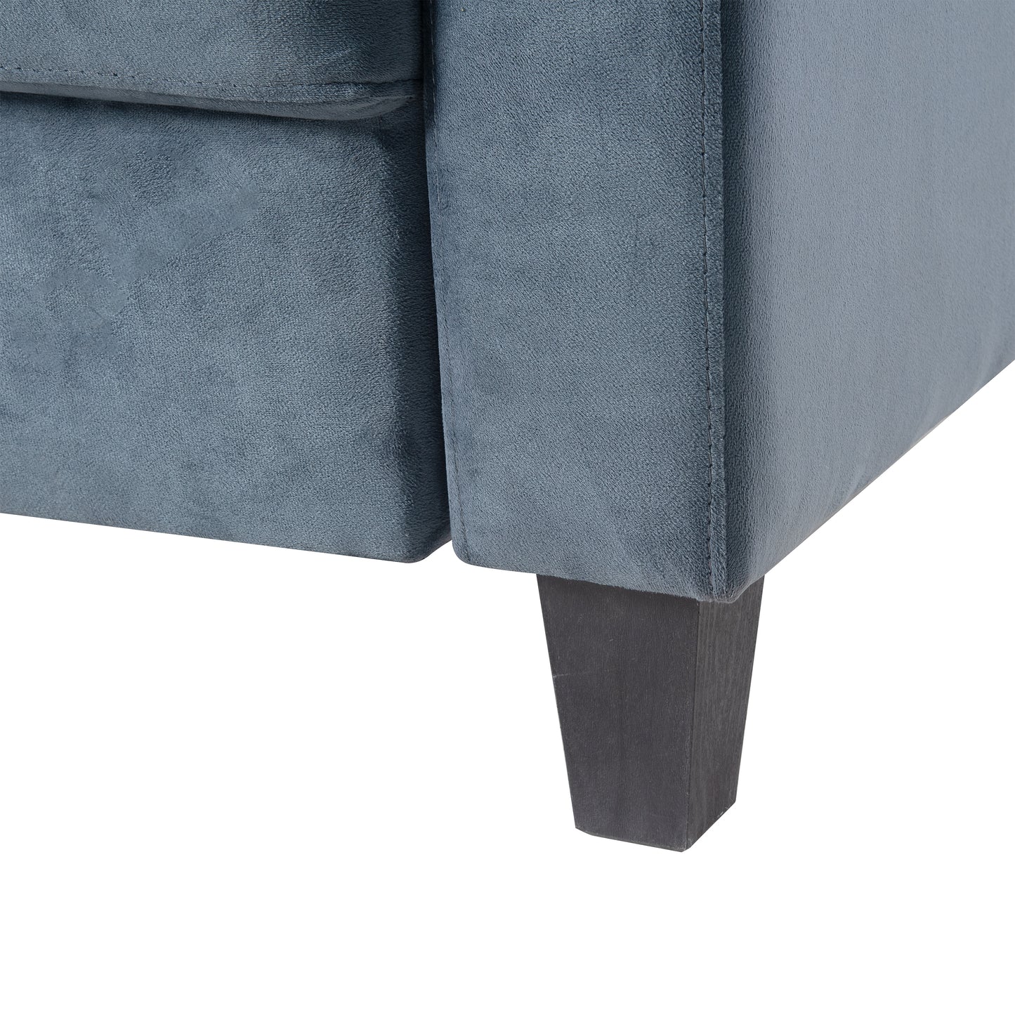 Closeup of a grey velvet armchair showing stitched seams and a dark wooden tapered leg