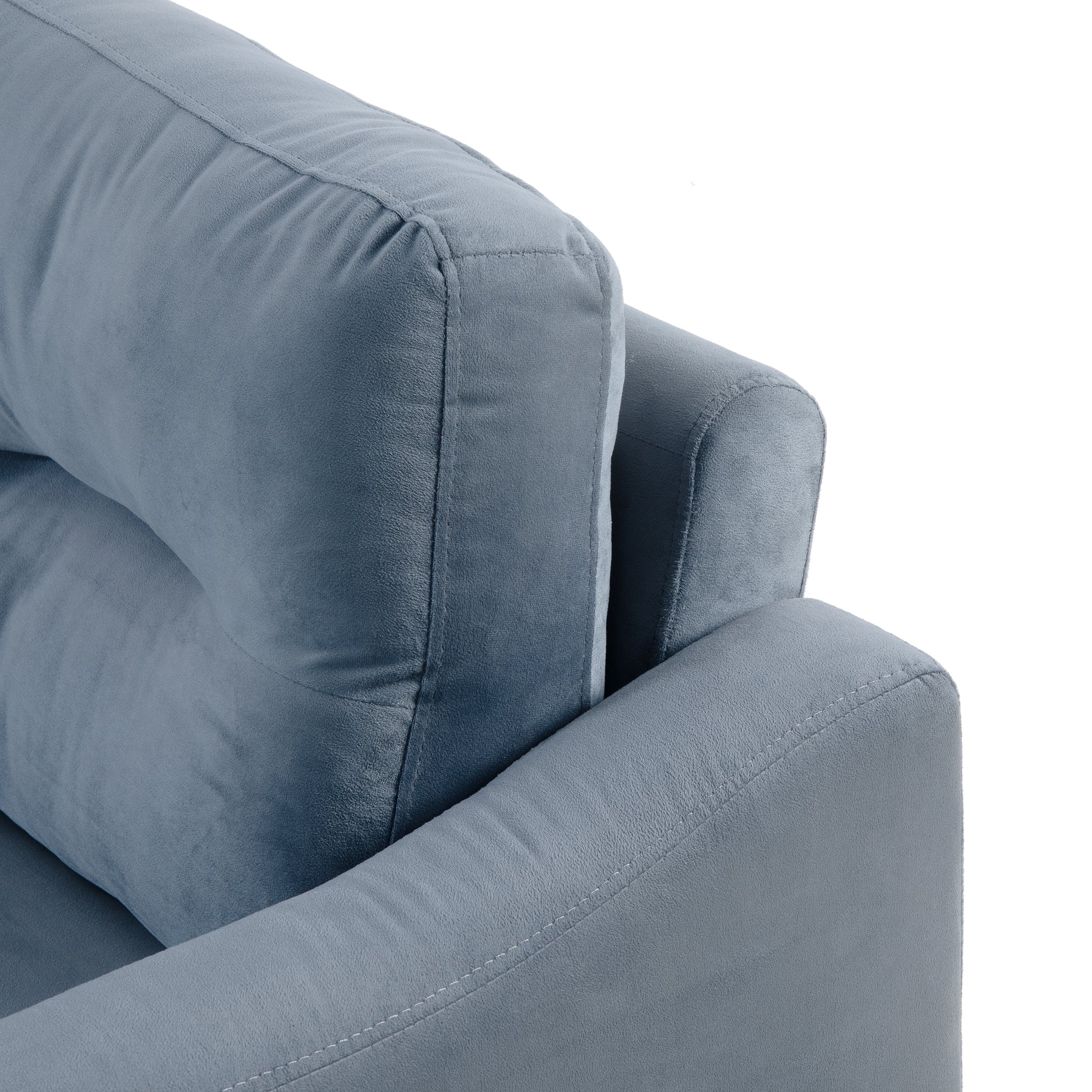 Closeup of plush blue velvet sofa armrest and cushion with subtle stitching detail