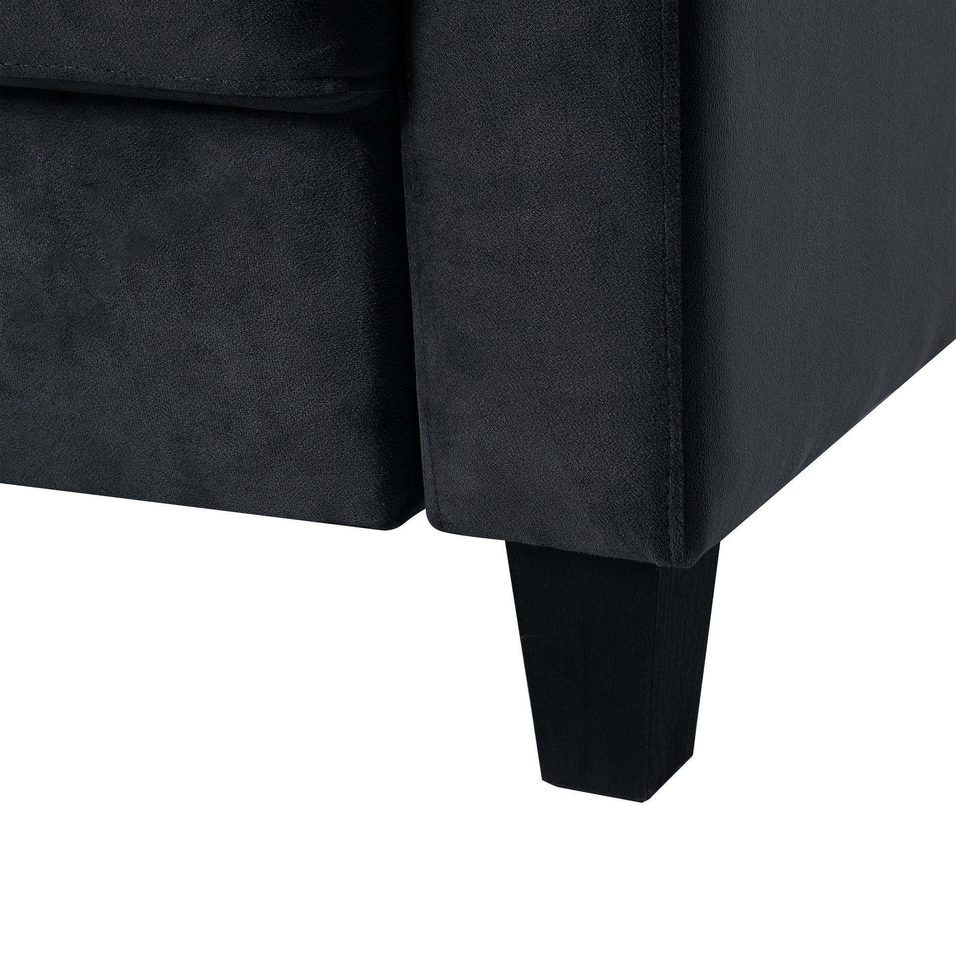 Closeup of a black velvet sofa arm with a tapered wooden leg