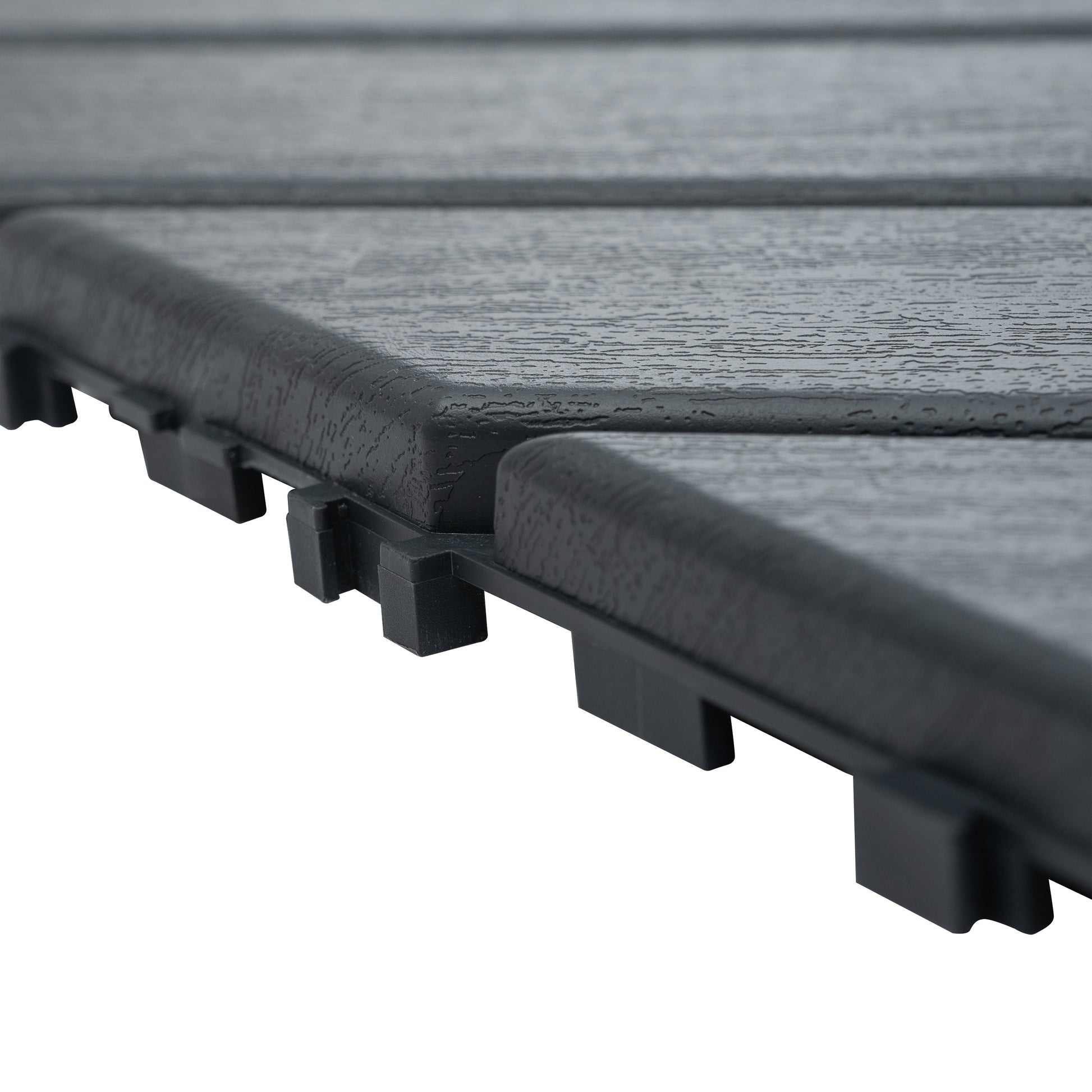 Closeup of interlocking dark gray composite deck tiles with a wood grain texture