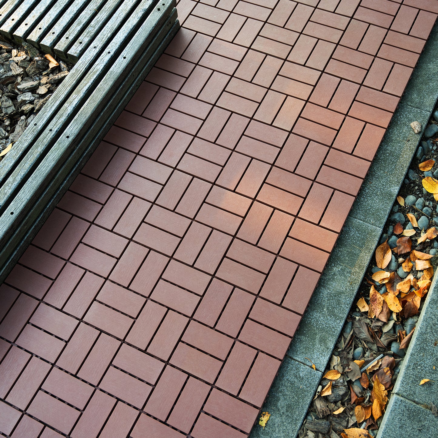 Rich brown interlocking deck tiles with a wood grain finish creating a herringbone pattern for outdoor patios