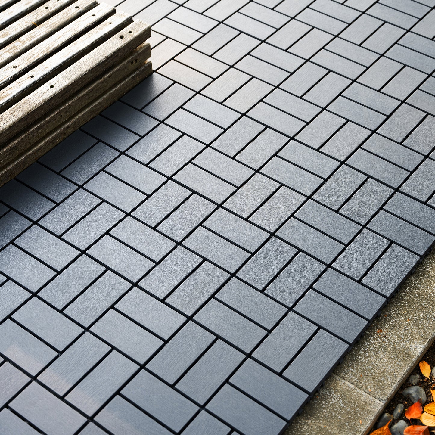 Gray interlocking composite deck tiles in a herringbone pattern