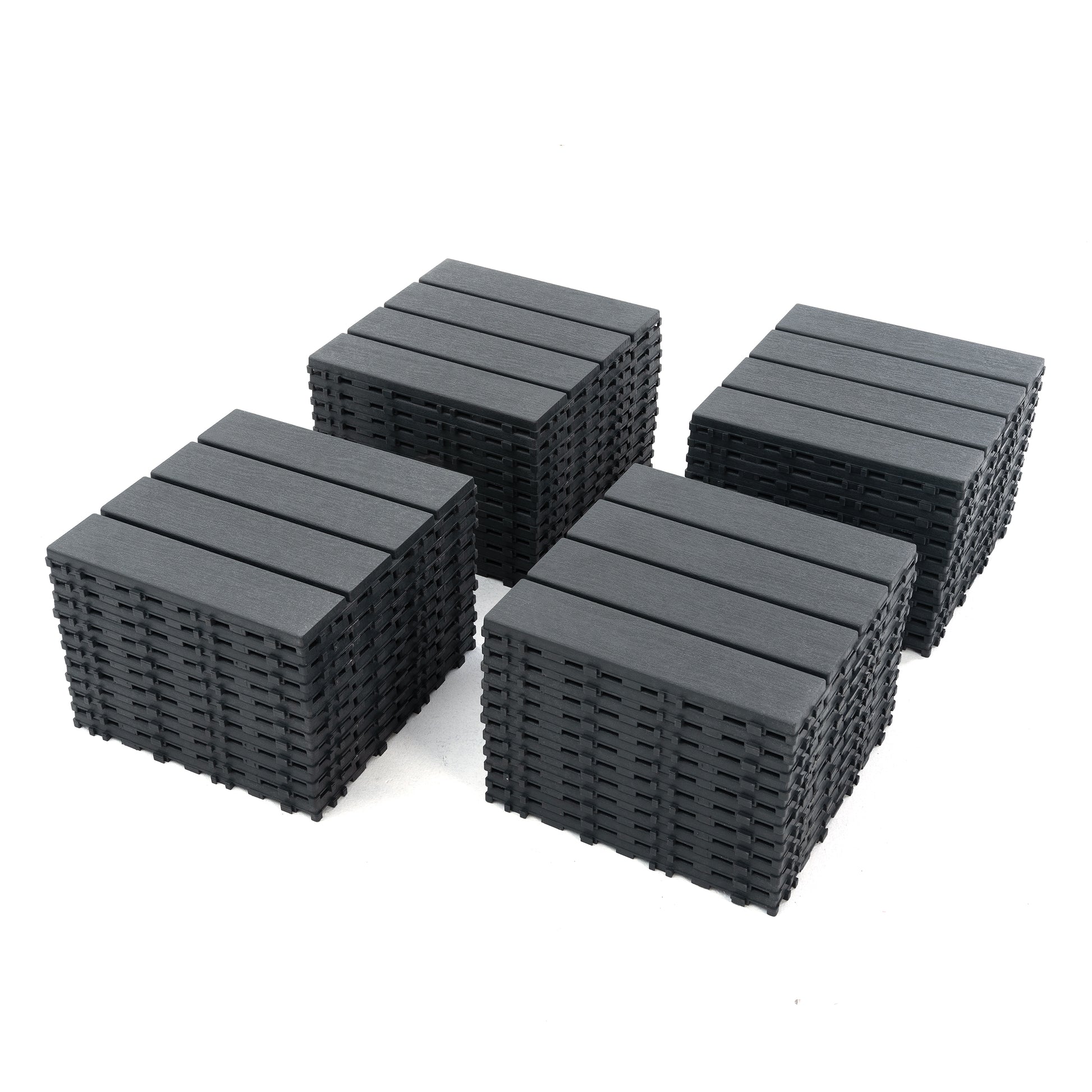 Four stacks of dark gray interlocking composite deck tiles designed for easy DIY patio installation