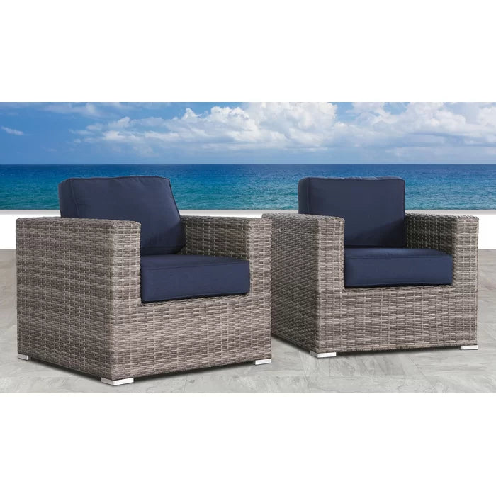 Gray wicker patio chairs with navy blue cushions on a tiled patio overlooking the ocean