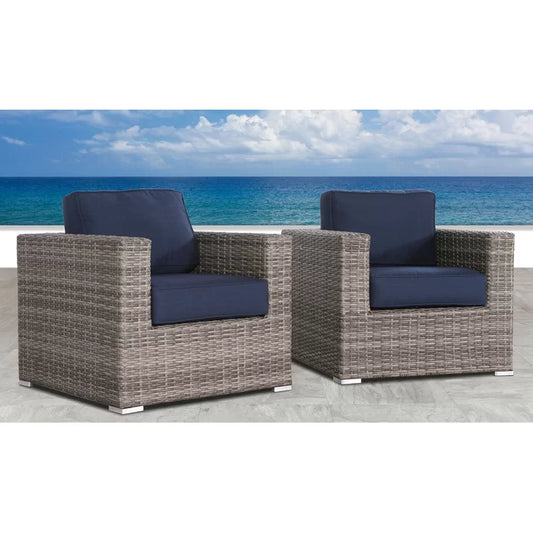 Gray wicker patio chairs with navy blue cushions on a tiled patio overlooking the ocean
