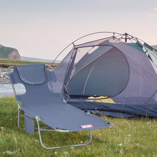 Gray folding camping cot with headrest and side pocket set up on grass near a tent