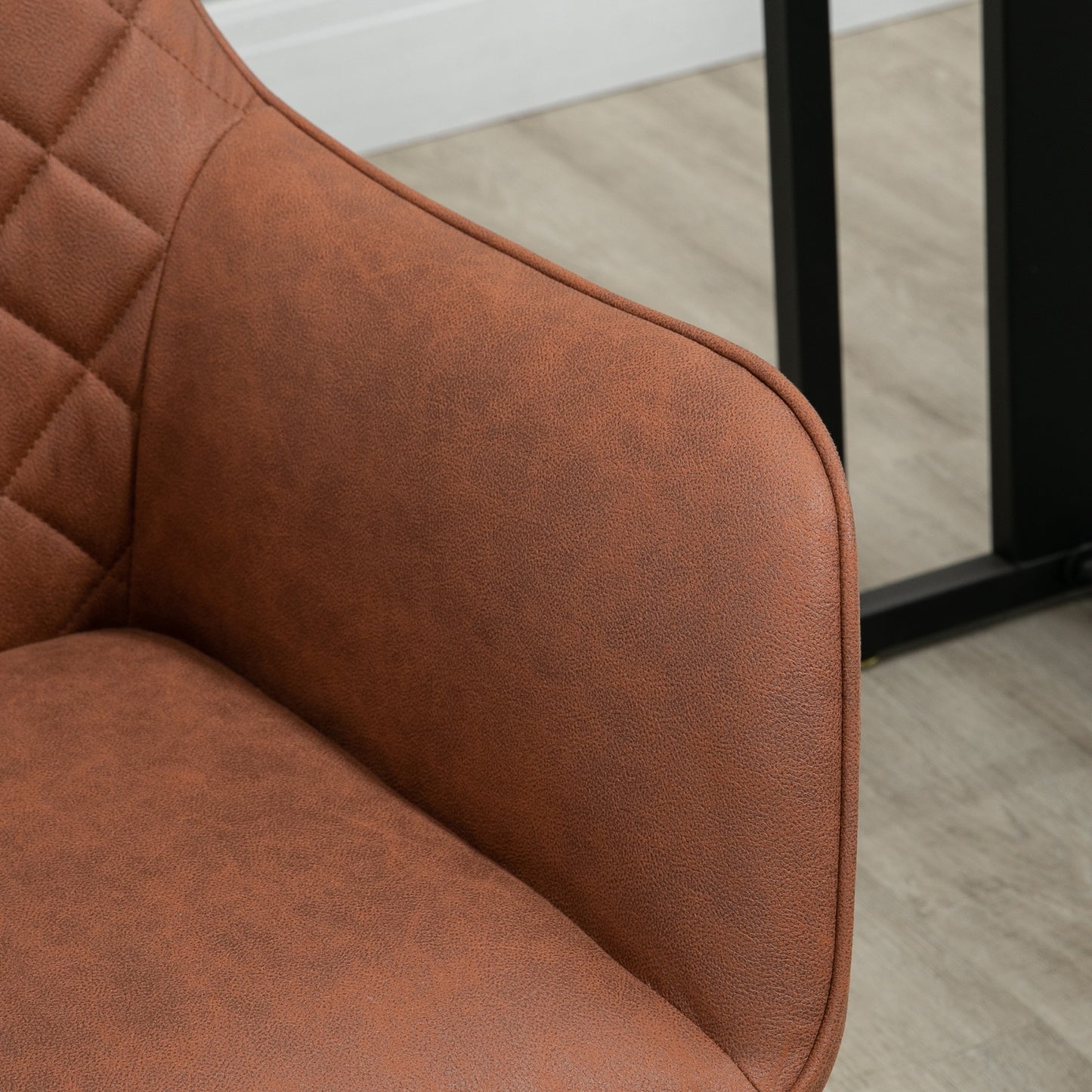 Closeup of a brown upholstered armchair with diamond stitching detail on armrest