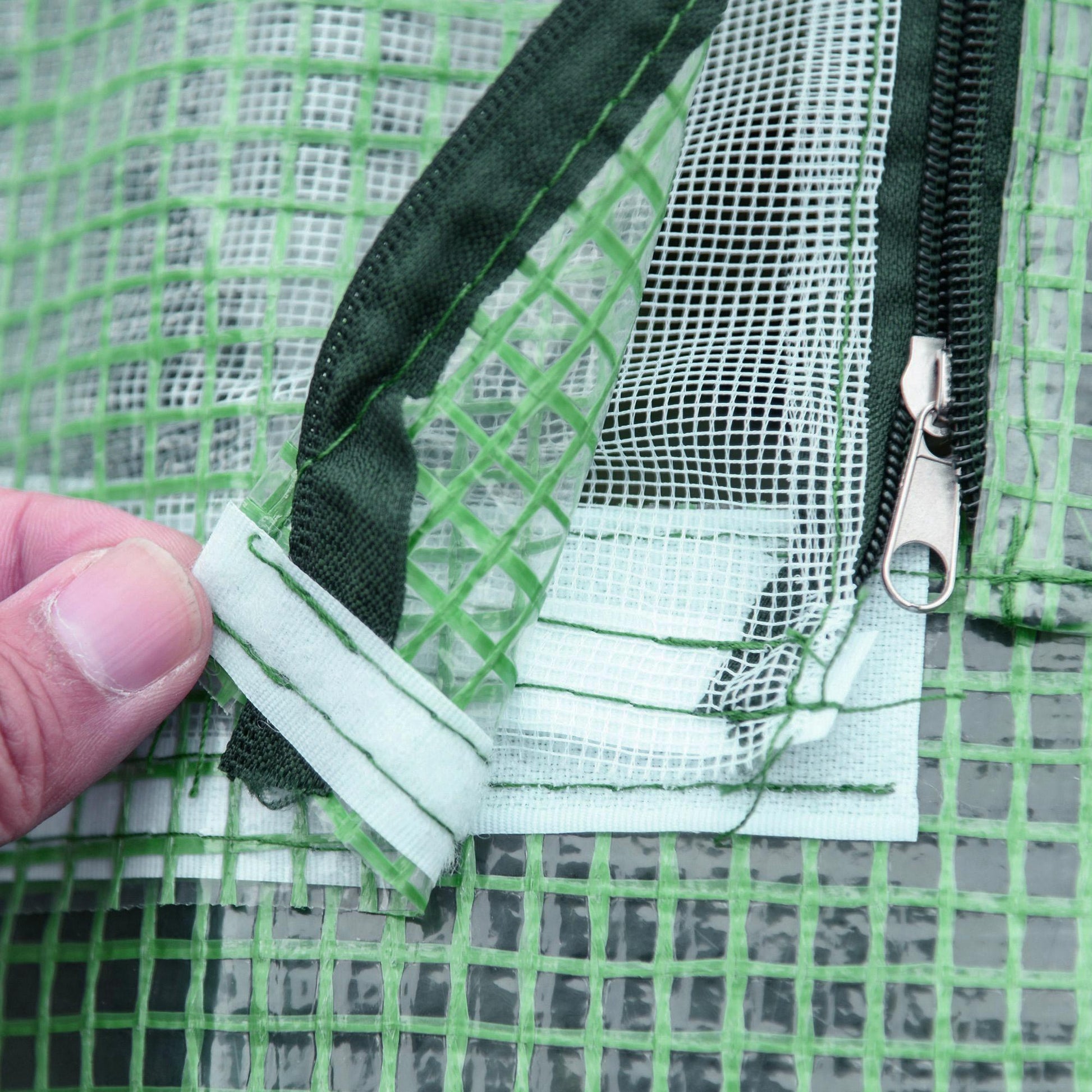Closeup of green greenhouse cover detail showing mesh and zipper closure ideal for garden structures
