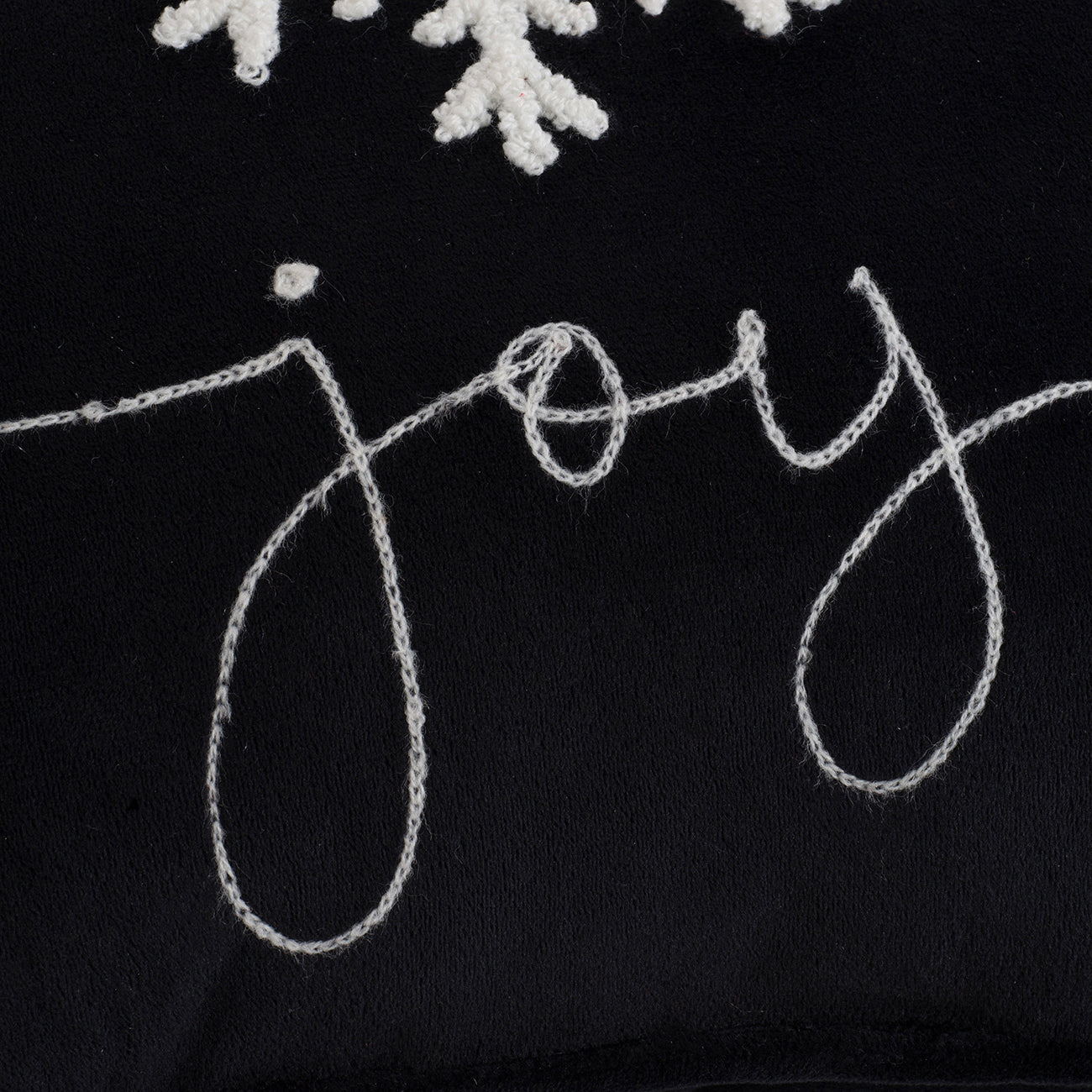 Black throw pillow with white embroidered Joy text and snowflake details