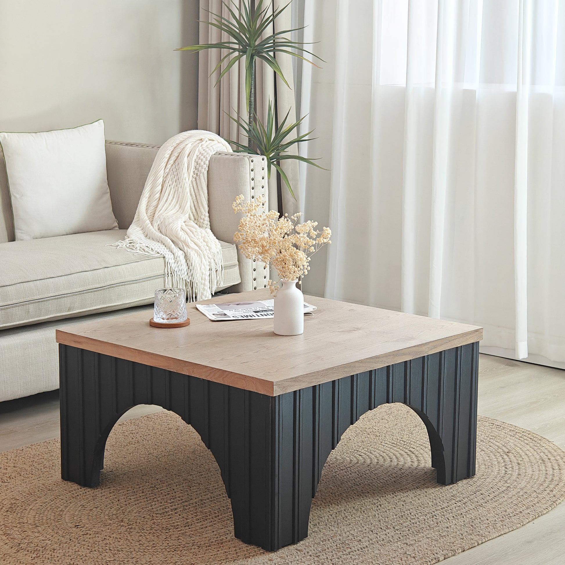 Square coffee table with light wood top and fluted black base