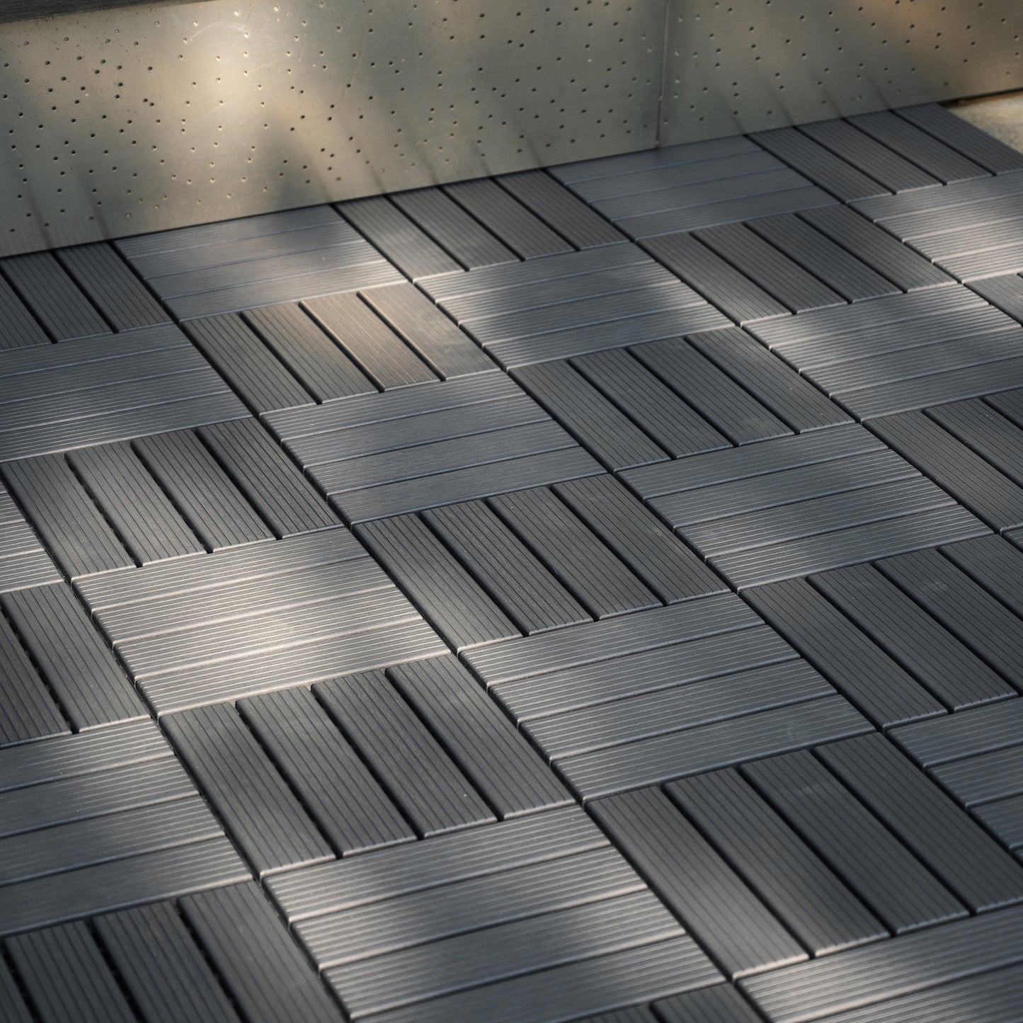 Dark grey composite deck tiles with a woodgrain texture interlocking for outdoor patio flooring