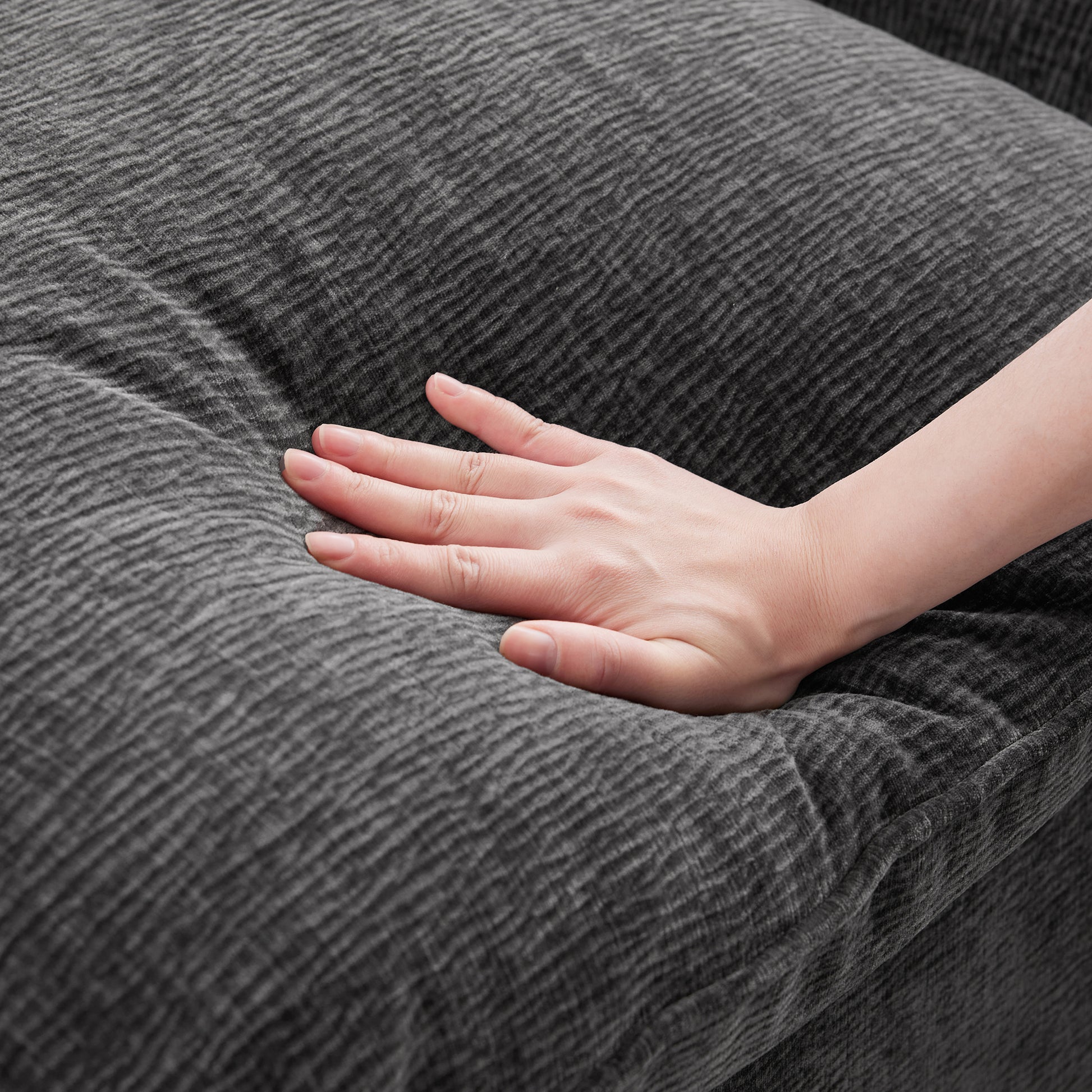 Closeup of hand testing soft dark gray corduroy fabric of a sofa cushion