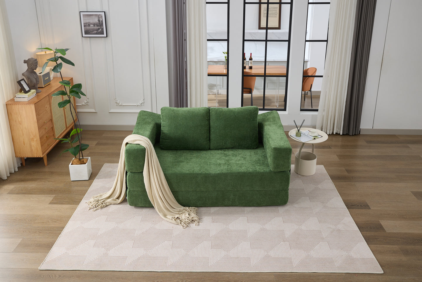 Plush green sofa bed with cream throw draped over the armrest perfect for small spaces
