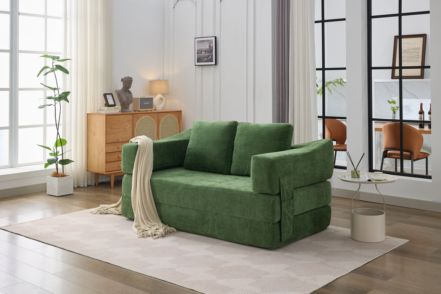 Green velvet sofa bed with plush cushions and a cream throw