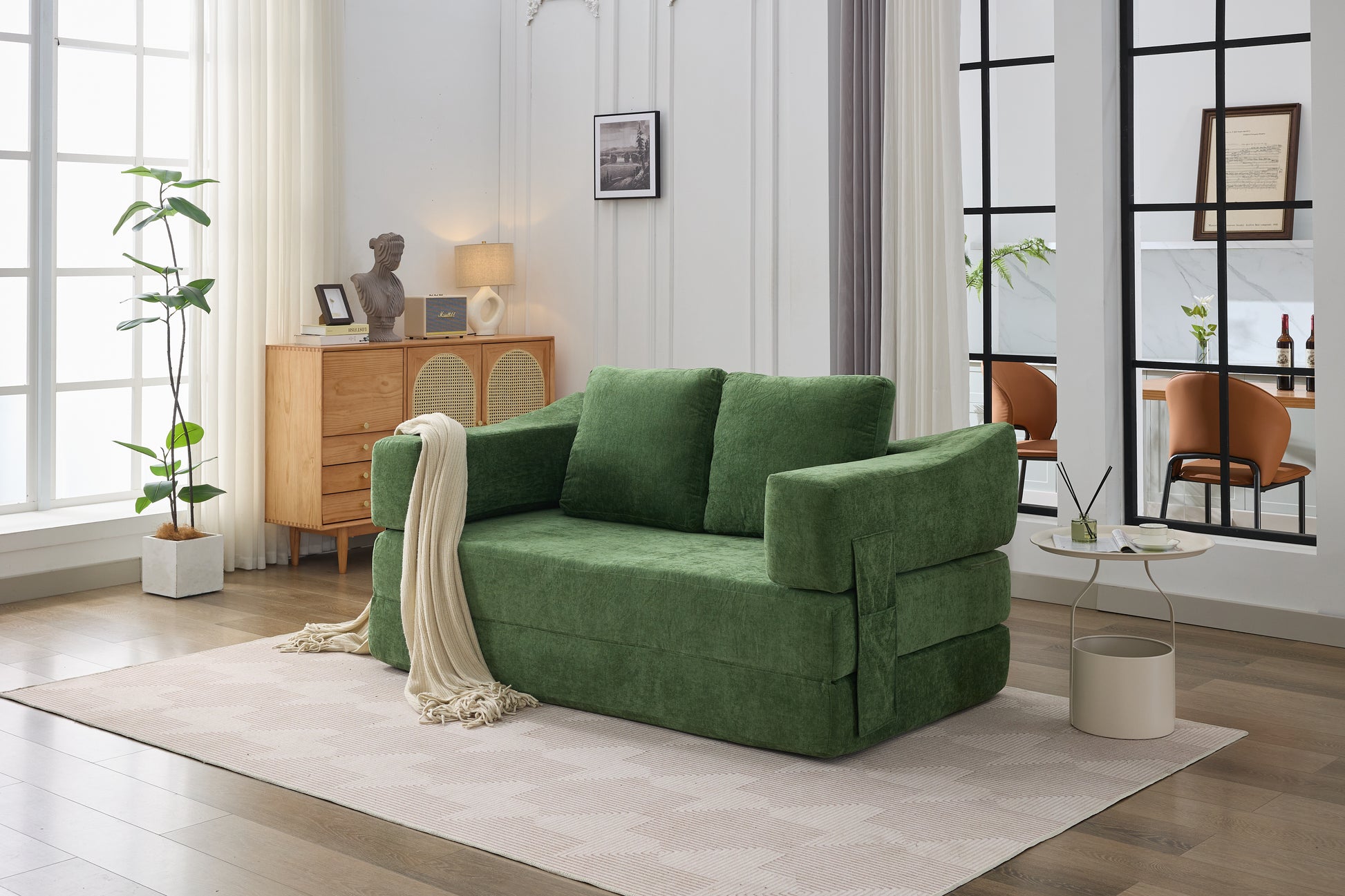 Green velvet sofa bed with plush cushions and a cream throw