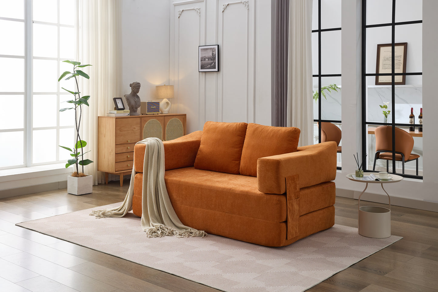 Terracotta orange futon sofa with plush cushions and a light throw blanket draped over the arm