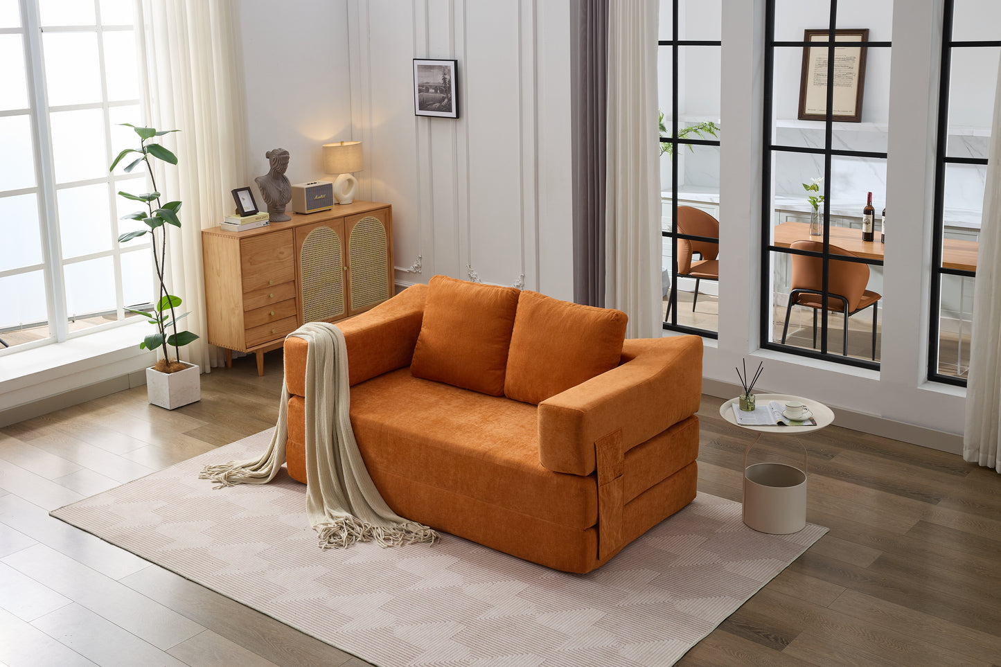 Orange fabric futon sofa with beige throw blanket in a modern living room setting
