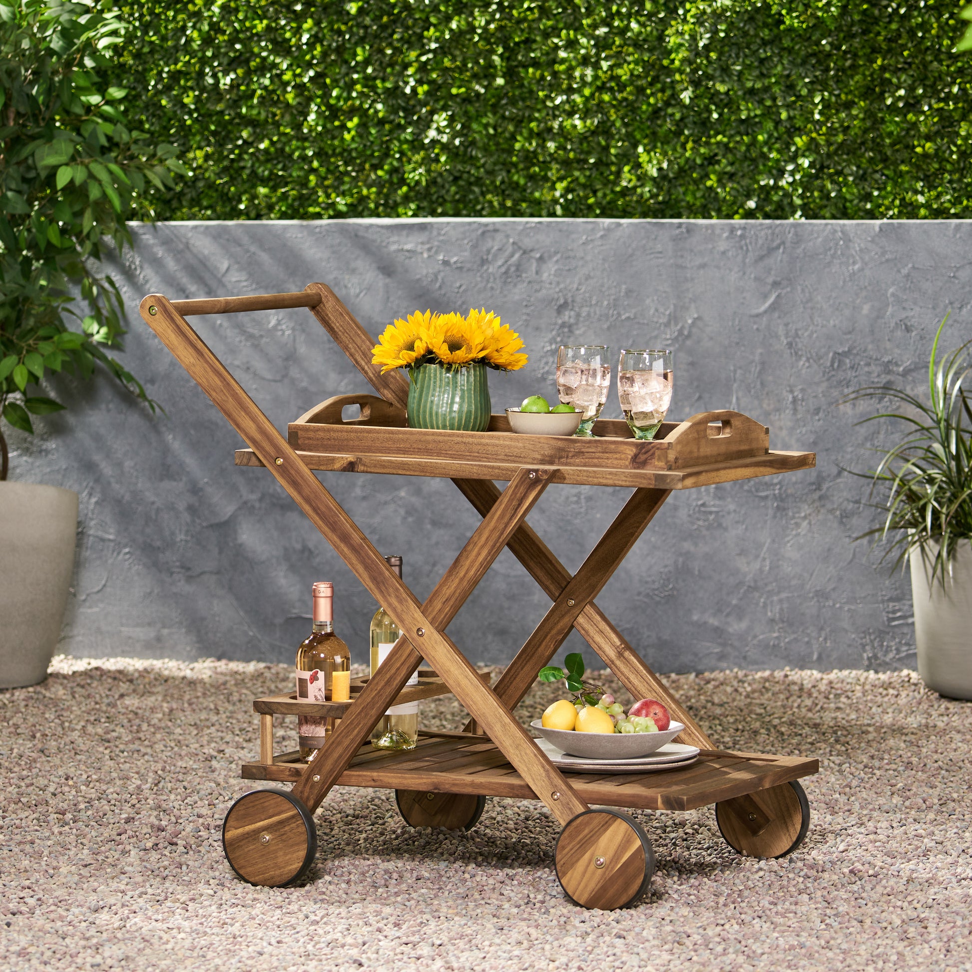 Wooden bar cart with two shelves holding drinks and sunflowers