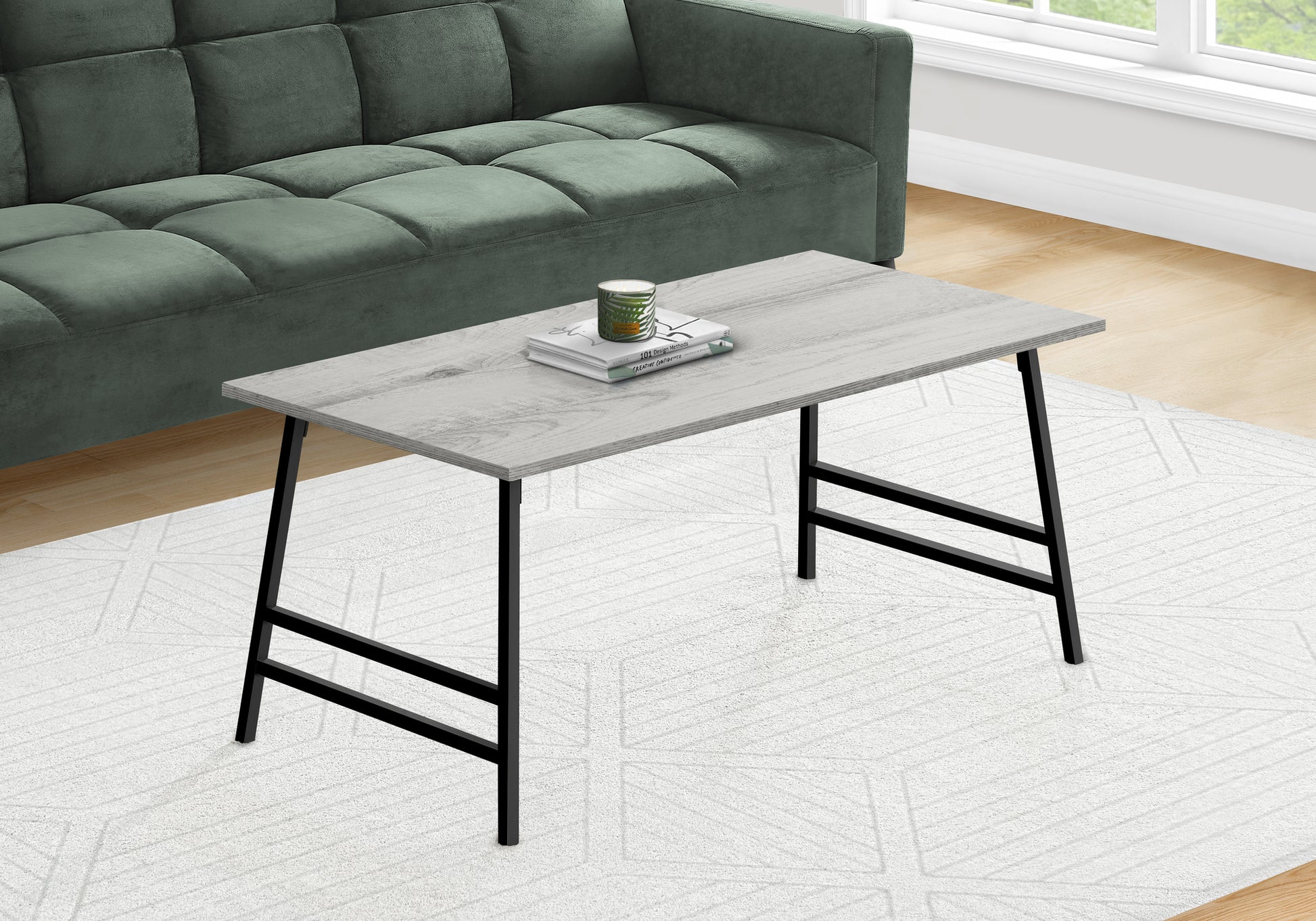 Light grey wood grain coffee table with black metal legs placed on a white rug