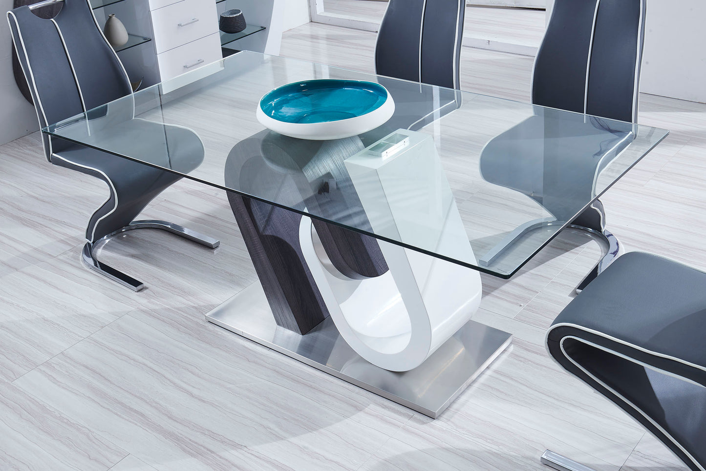 Modern glass dining table with a curved pedestal base and grey upholstered chairs