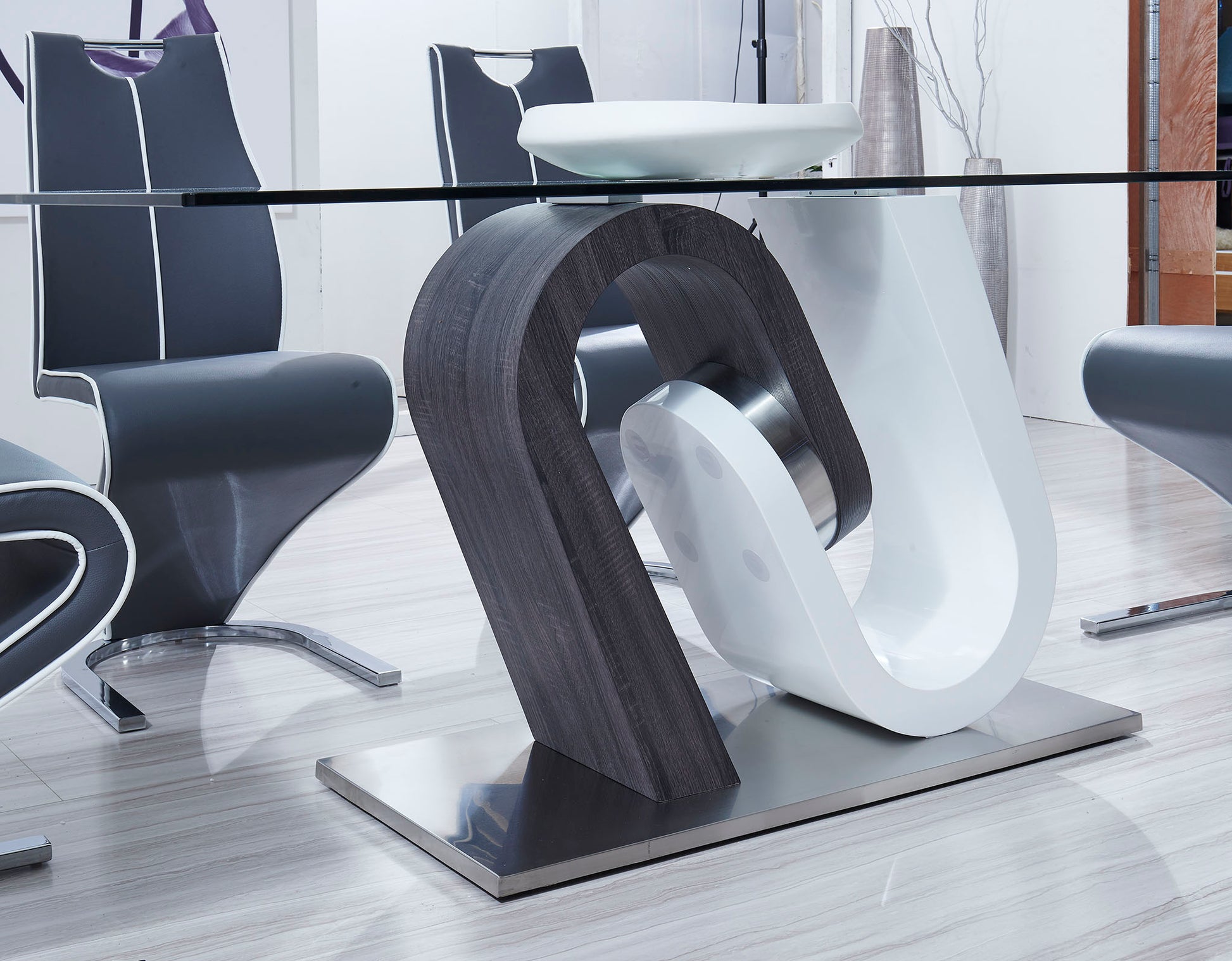 Modern glass dining table with a sculptural dark wood and white pedestal base