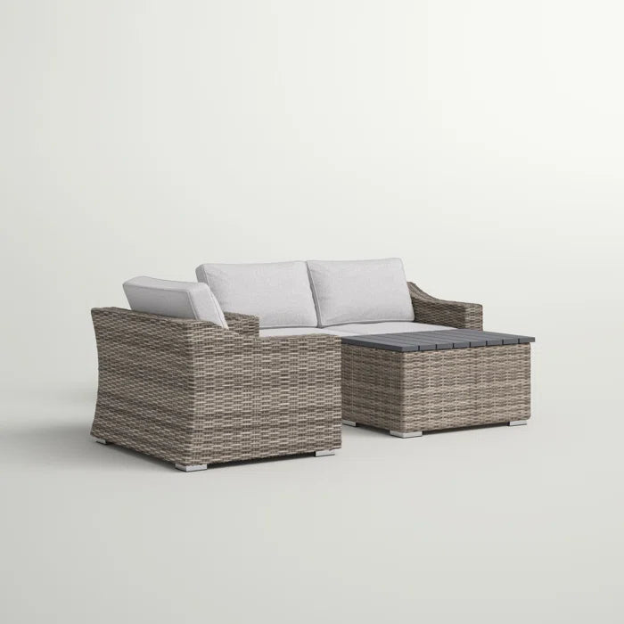 Gray wicker sectional sofa with white cushions and a dark gray wood slatted coffee table