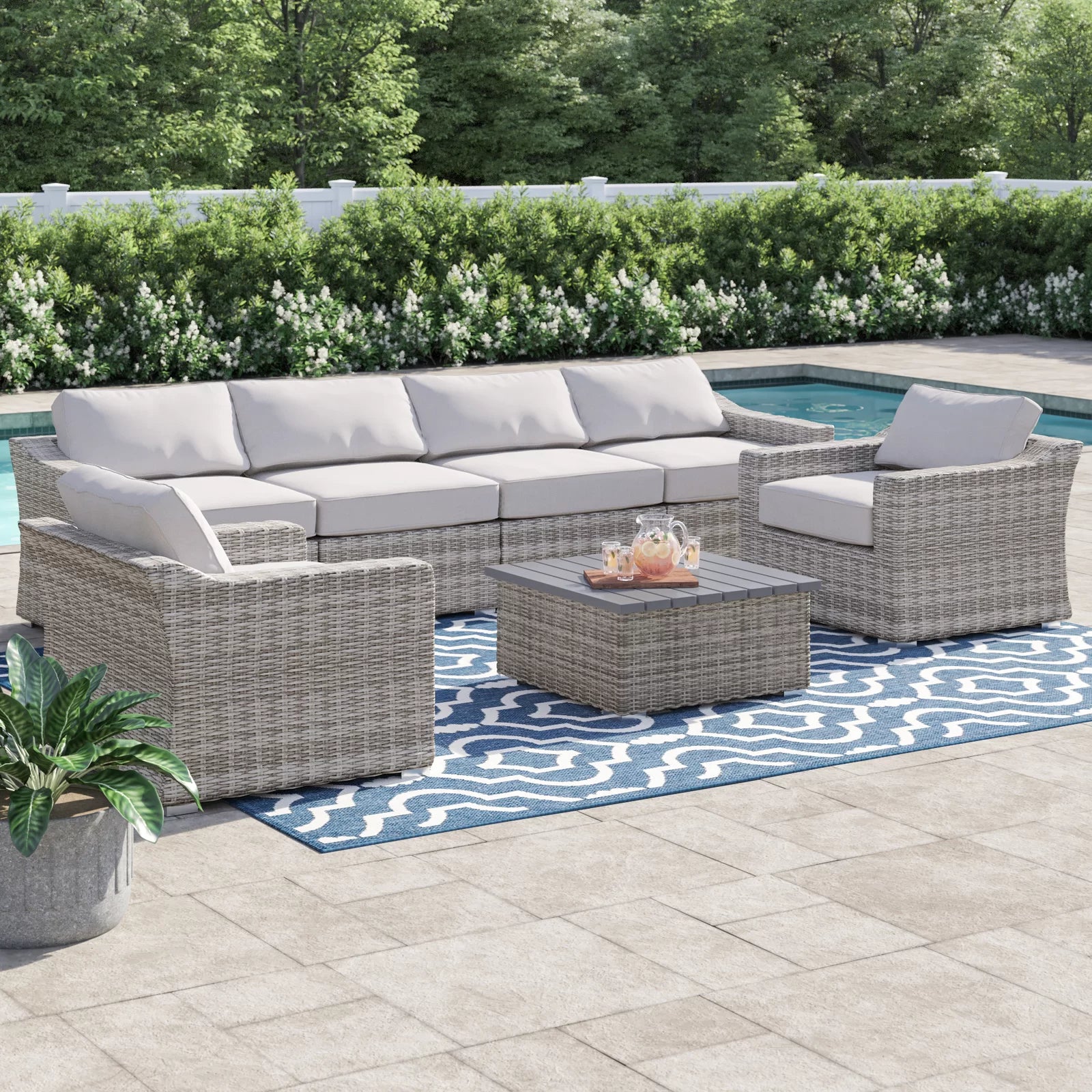 Gray wicker outdoor sectional sofa with plush white cushions and a matching coffee table