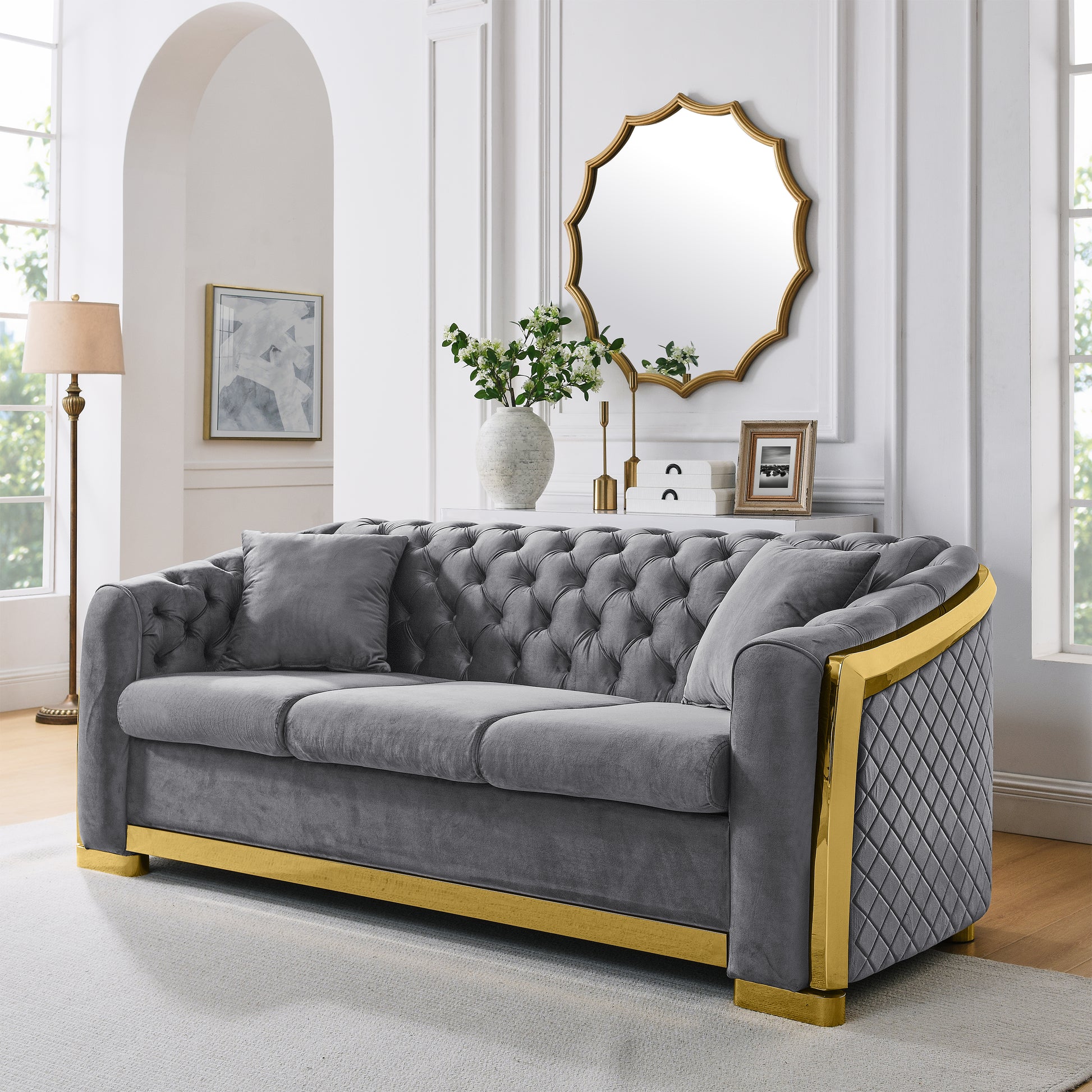 Grey tufted velvet sofa with gold trim and diamond quilting on arms