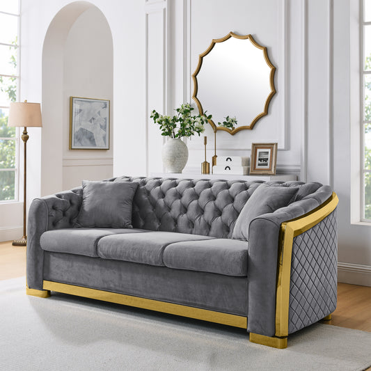Grey tufted velvet sofa with gold trim and diamond quilting on arms