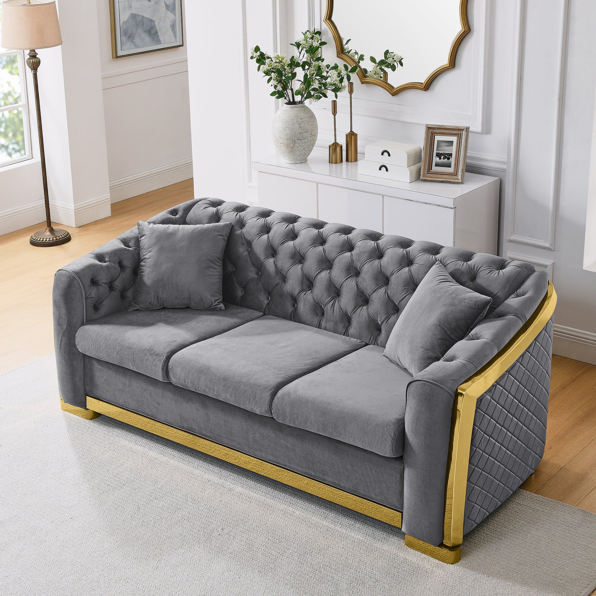 Luxurious grey velvet tufted sofa with gold accents and modern design