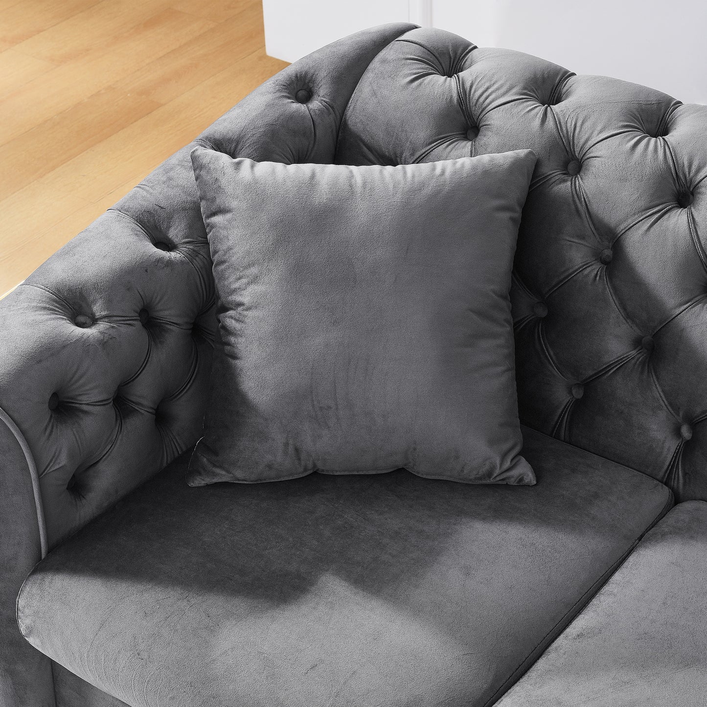 Dark grey velvet scatter cushion on a tufted chesterfield sofa