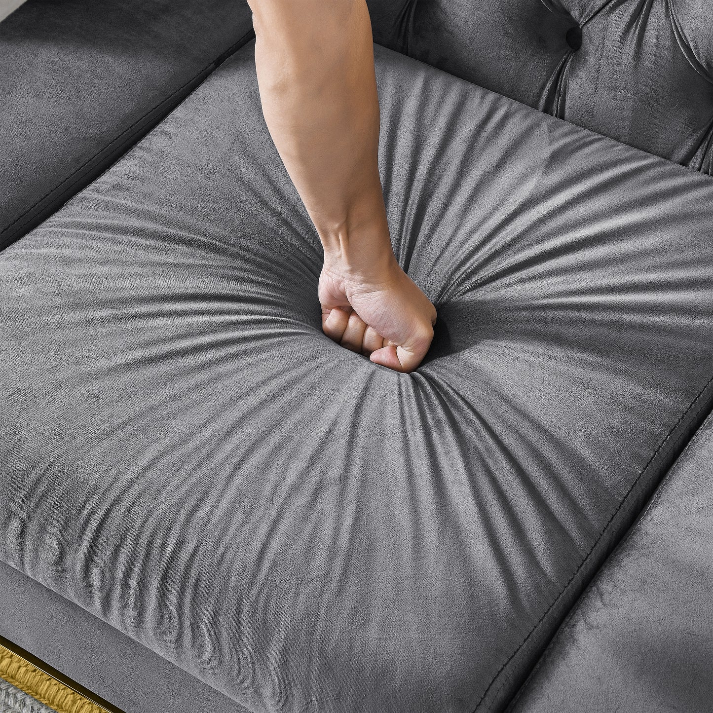 Closeup of hand pressing into soft dark grey velvet sofa cushion for comfort demonstration