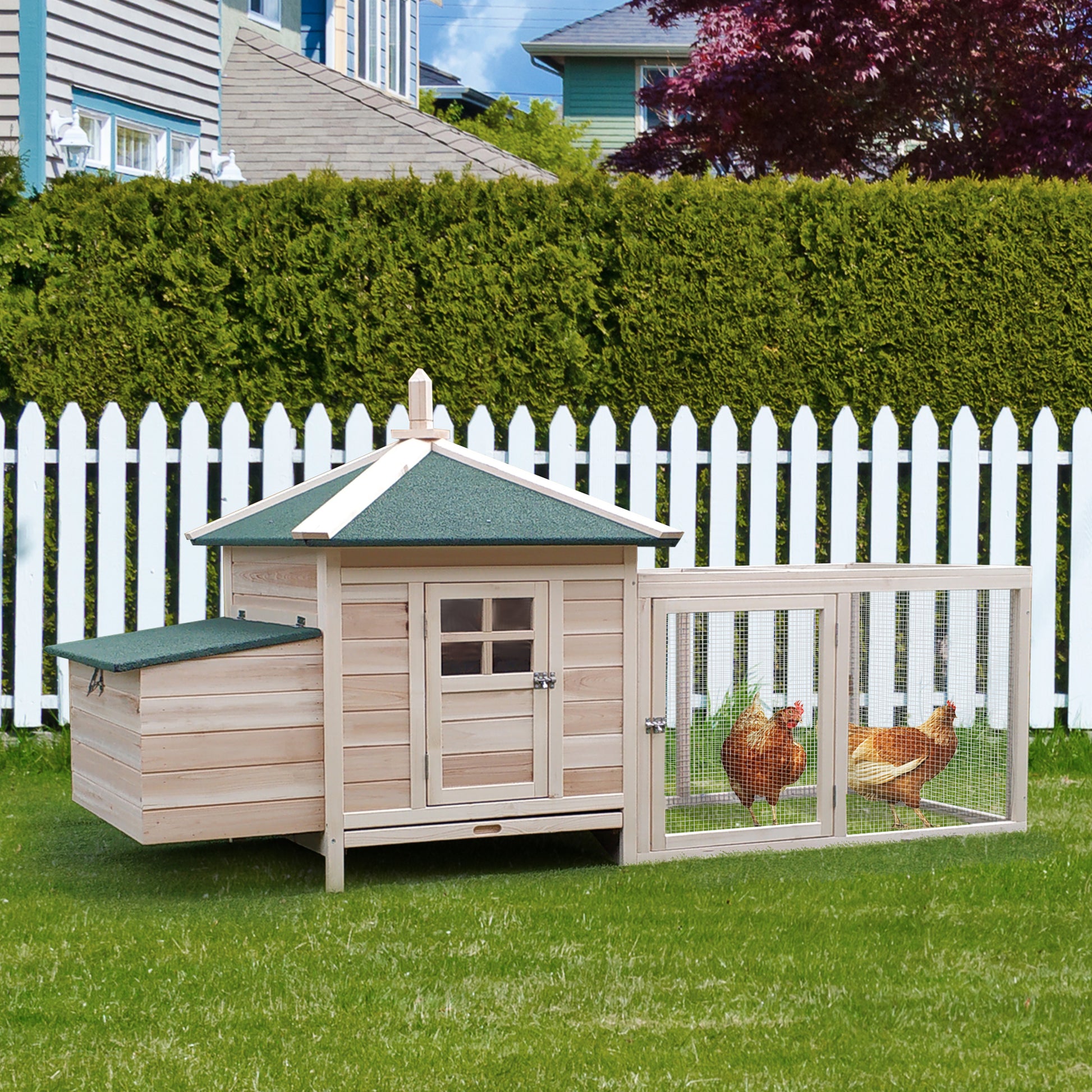 Twostory wooden chicken coop with green roof and attached run featuring two brown hens grazing
