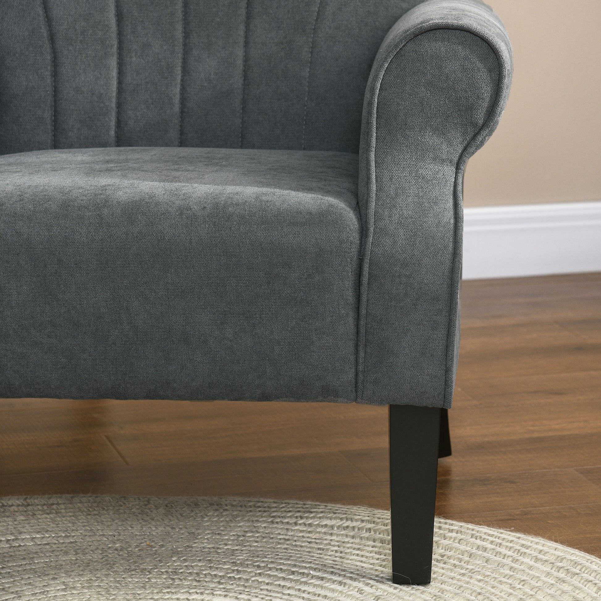 Dark gray upholstered accent chair with tufted back and rolled armrest